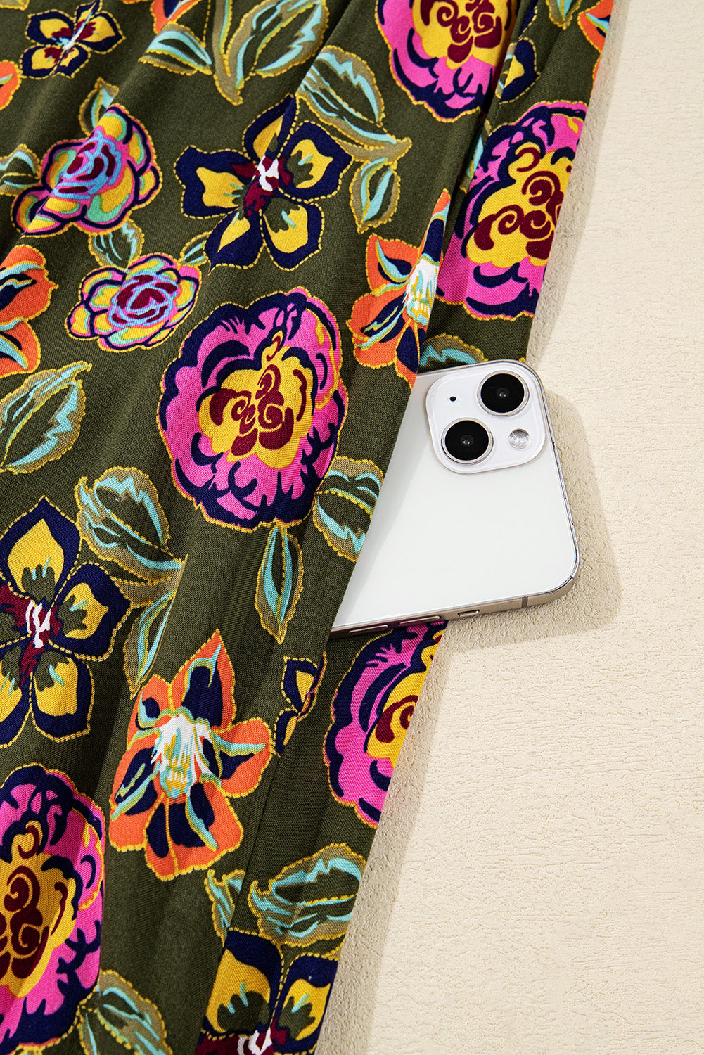 Green floral fabric with pink and yellow flowers, smartphone partially tucked in pocket