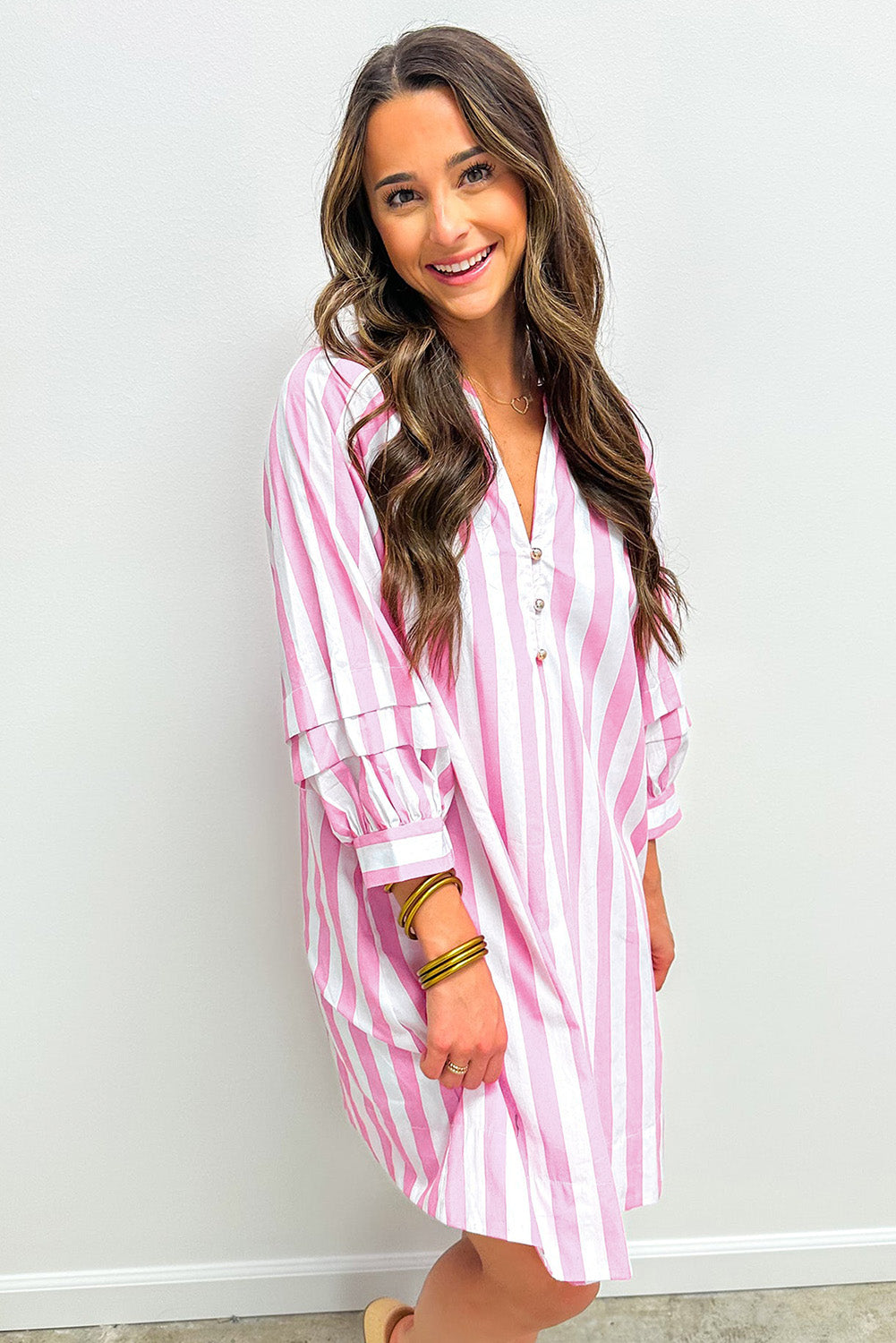 Woman wearing pink and white striped long-sleeve shirt dress, smiling indoors