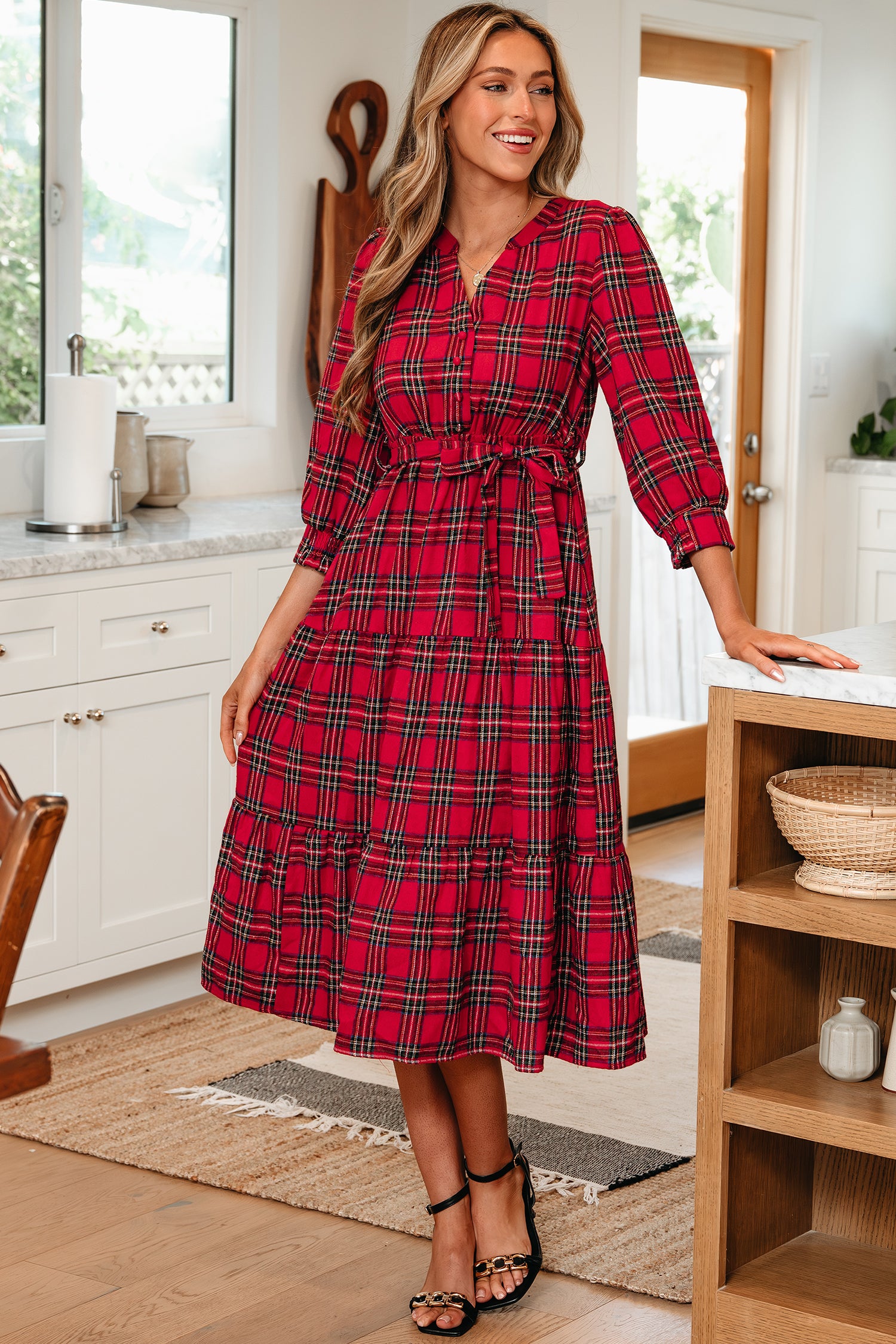 Woman in red plaid midi dress with belt, standing in a bright kitchen