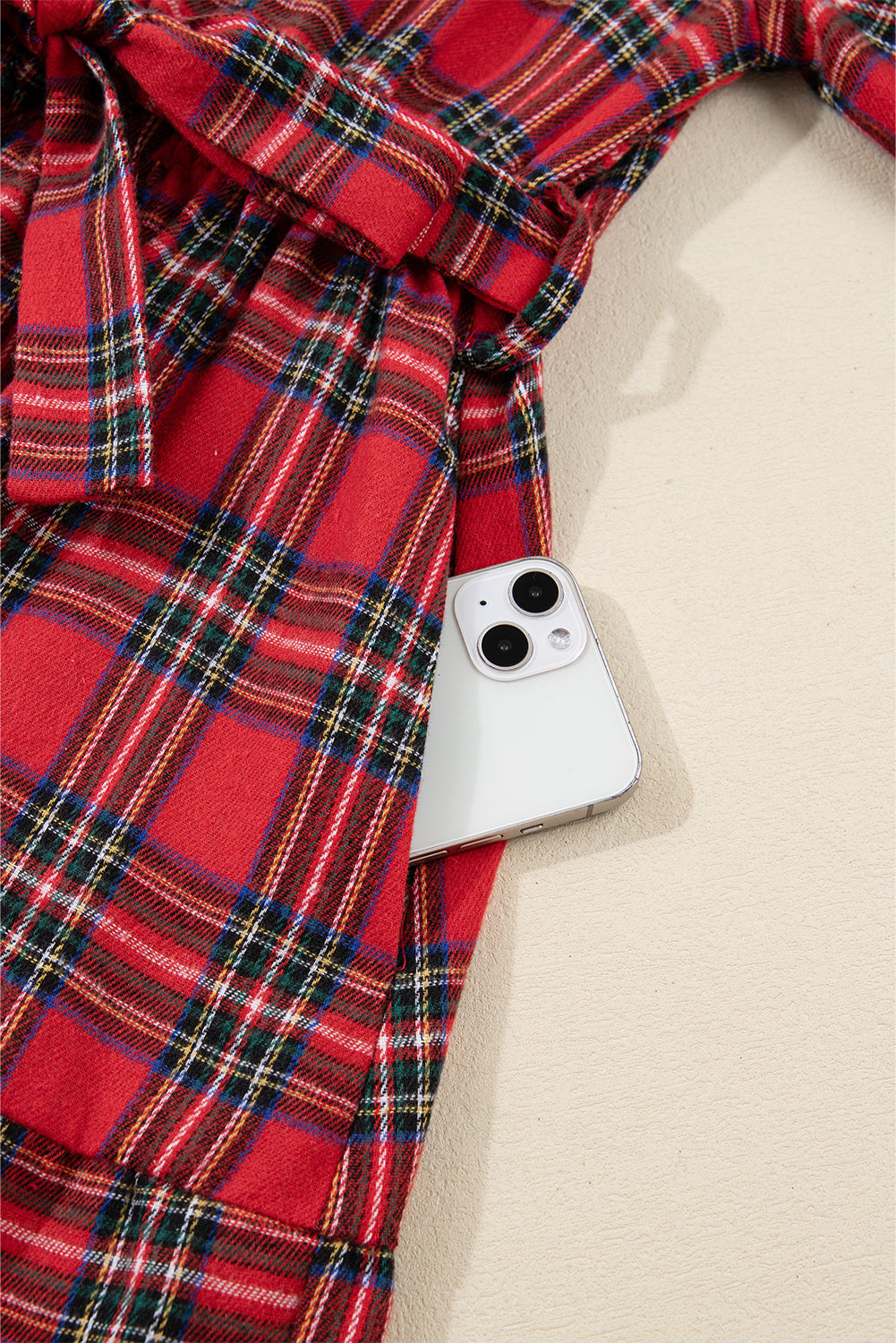 Red plaid dress with a white smartphone in the pocket, close-up detail view