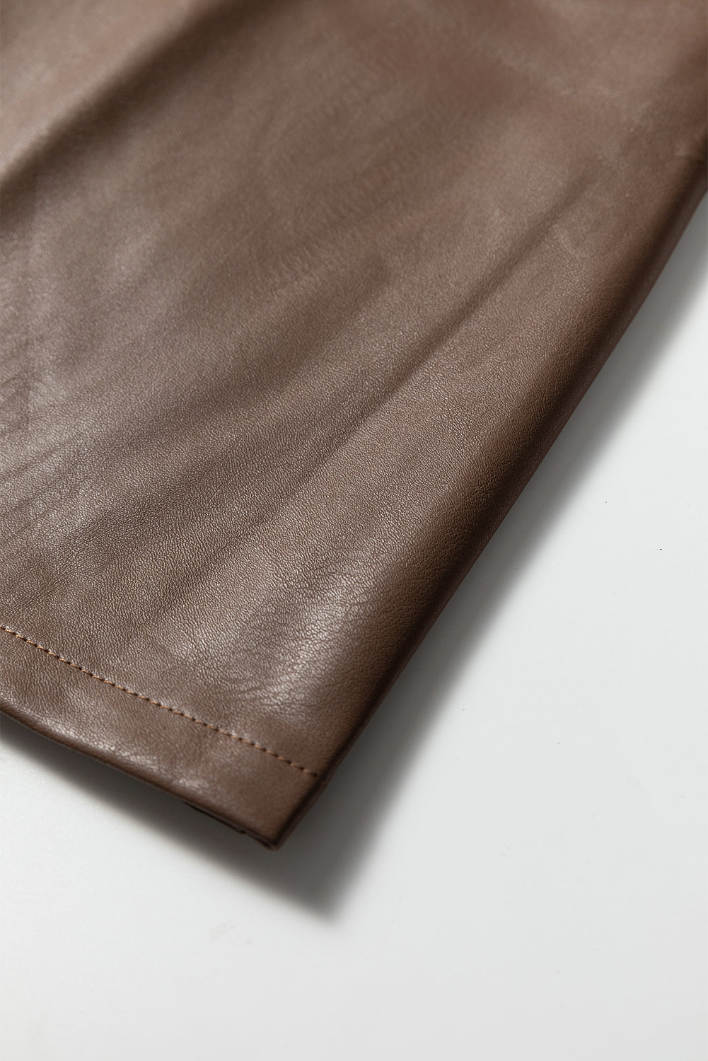 Close-up of brown faux leather fabric with visible stitching detail