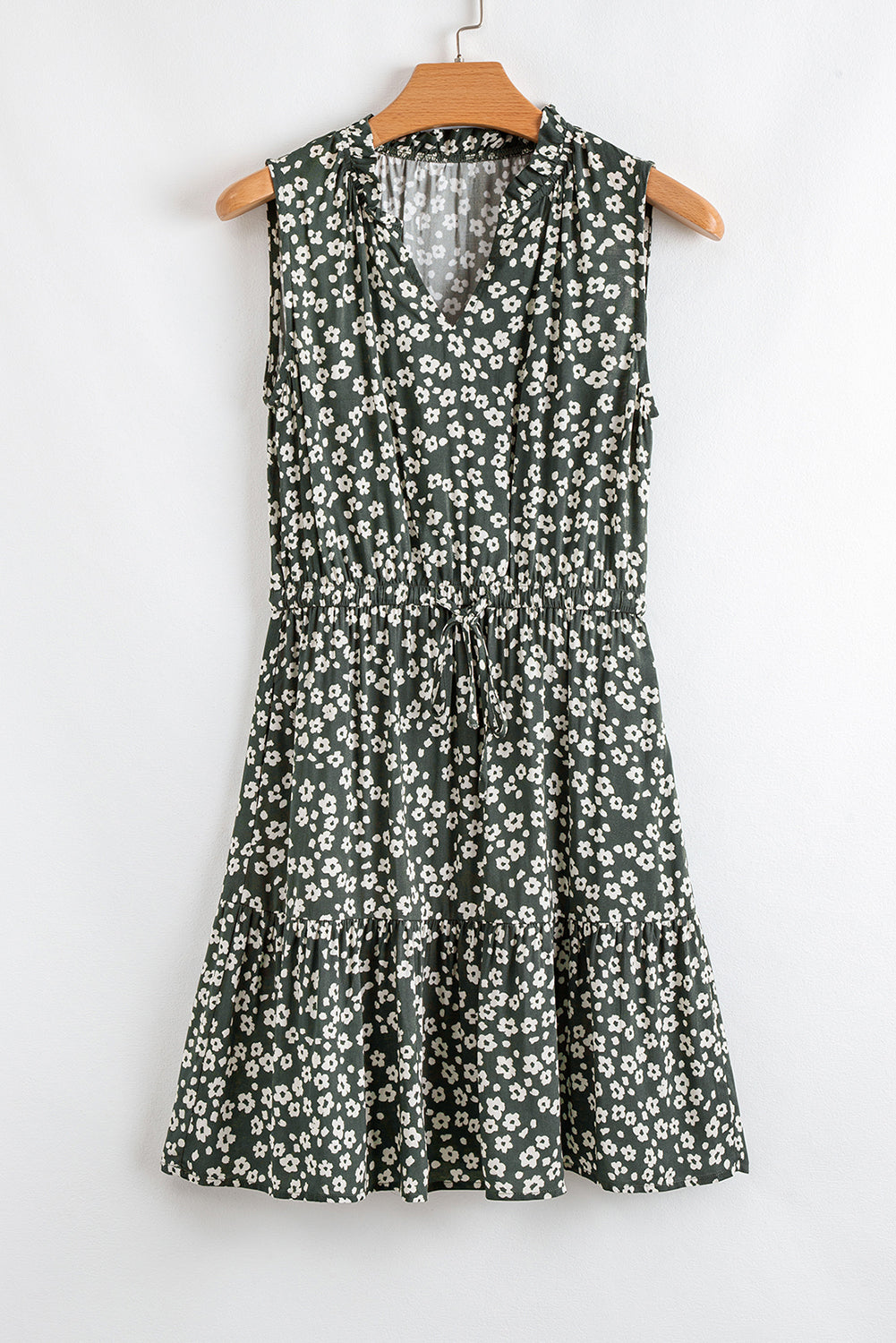 Sleeveless green floral dress with white daisy print and V-neck, hanging on wooden hanger