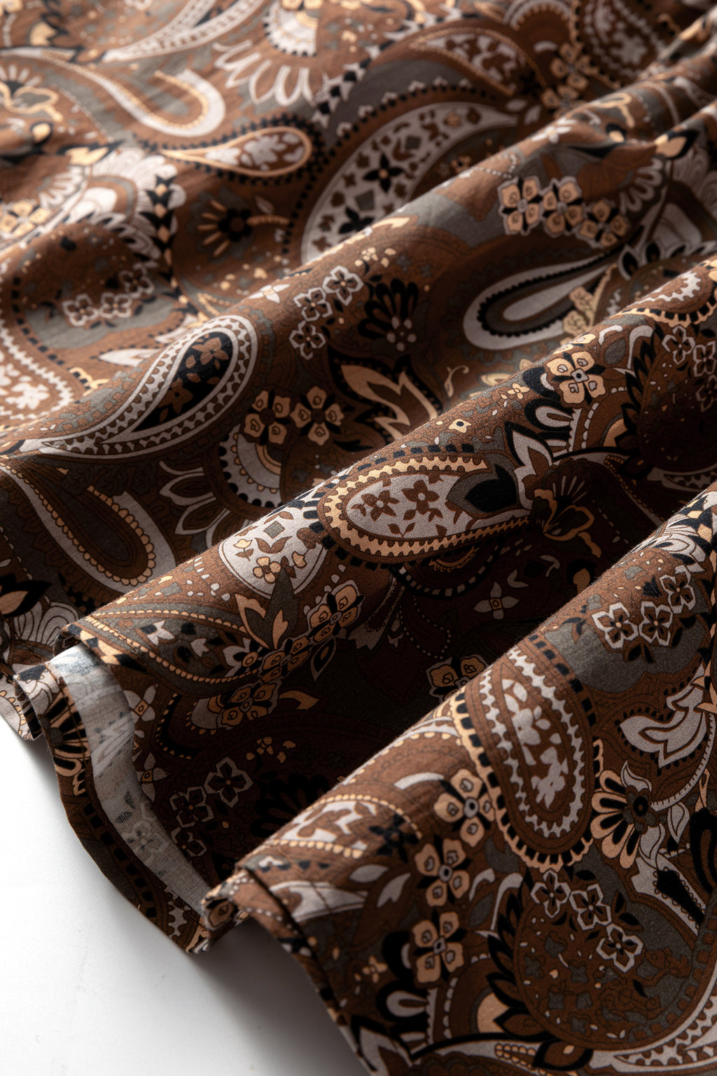 детайл на материята на дамска кафява рокля с пейсли принт, текстура на плат отблизо