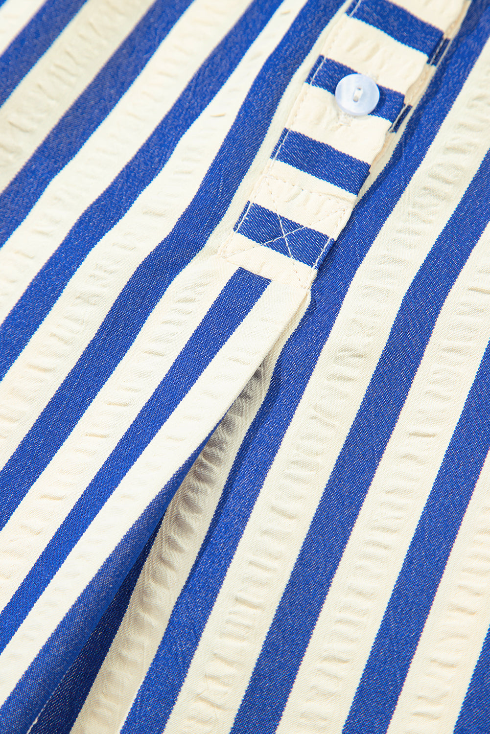 Close-up of blue and white striped shirt fabric with button detail