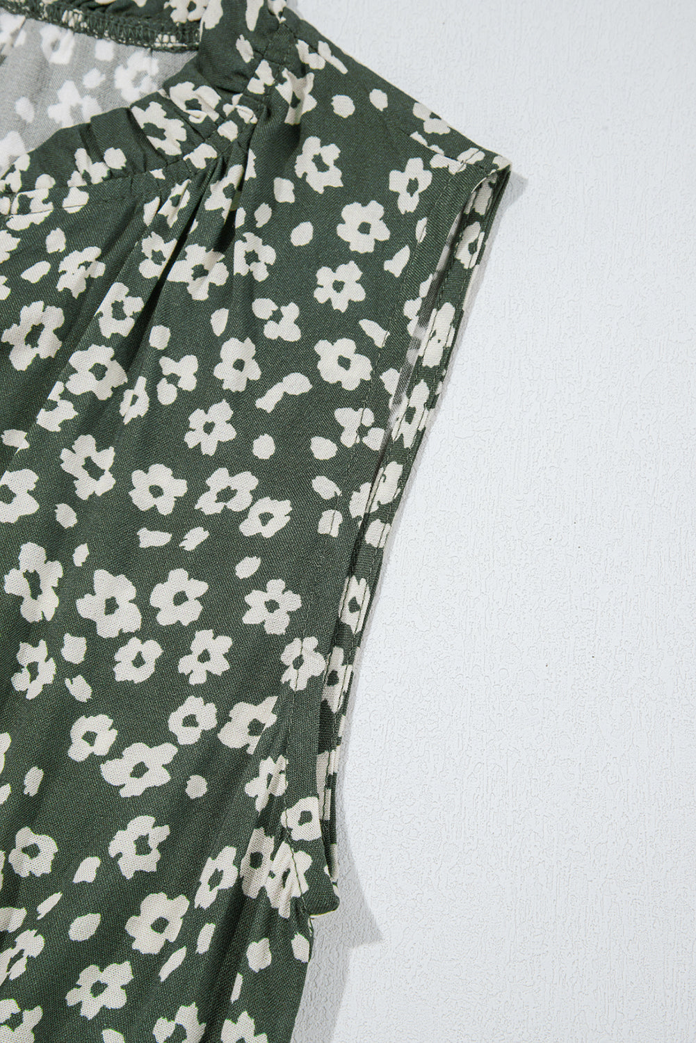 Green sleeveless blouse with white floral print detail on light background