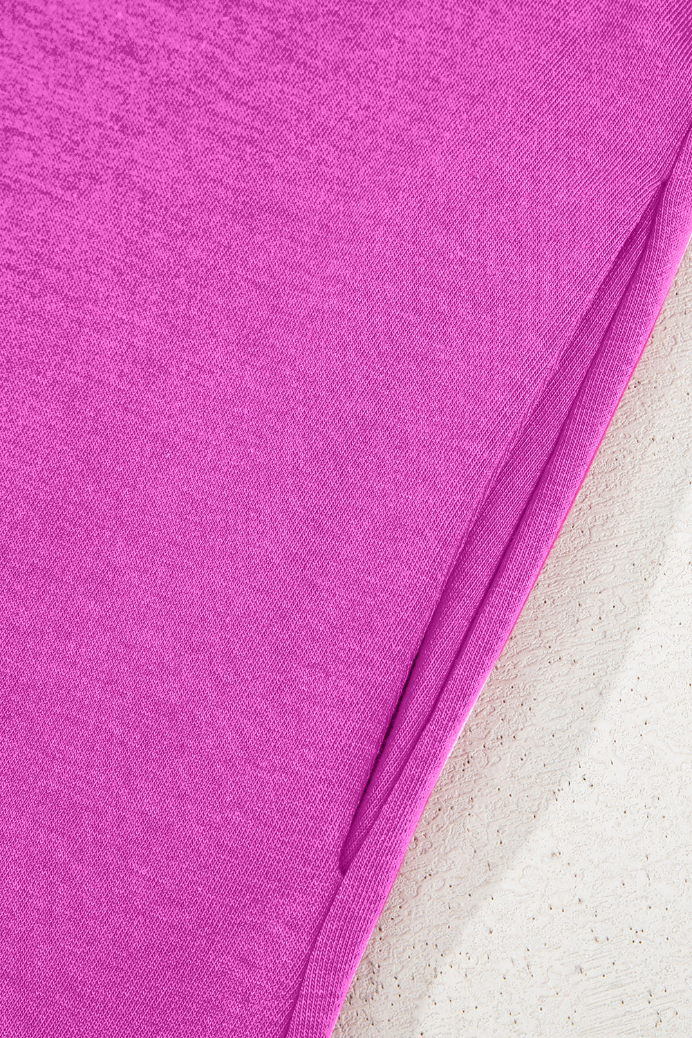 Close-up of pink textured fabric with clean seam detail on light background