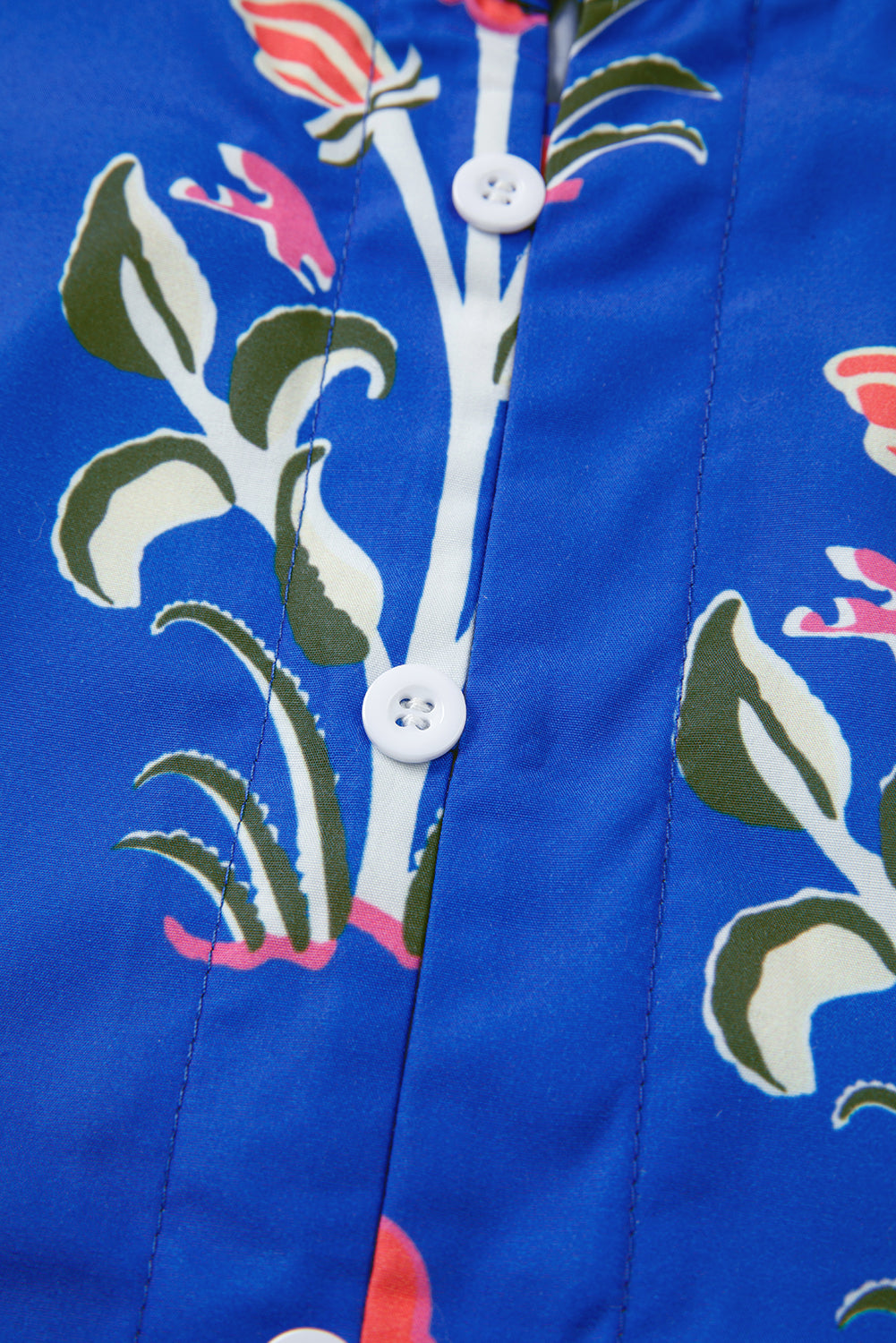 Blue floral patterned shirt fabric with white buttons, close-up detail