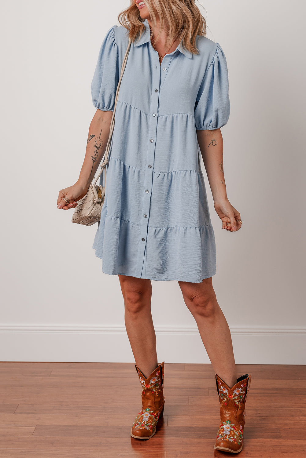 Woman in light blue button-front tiered dress with short puff sleeves and brown floral cowboy boots