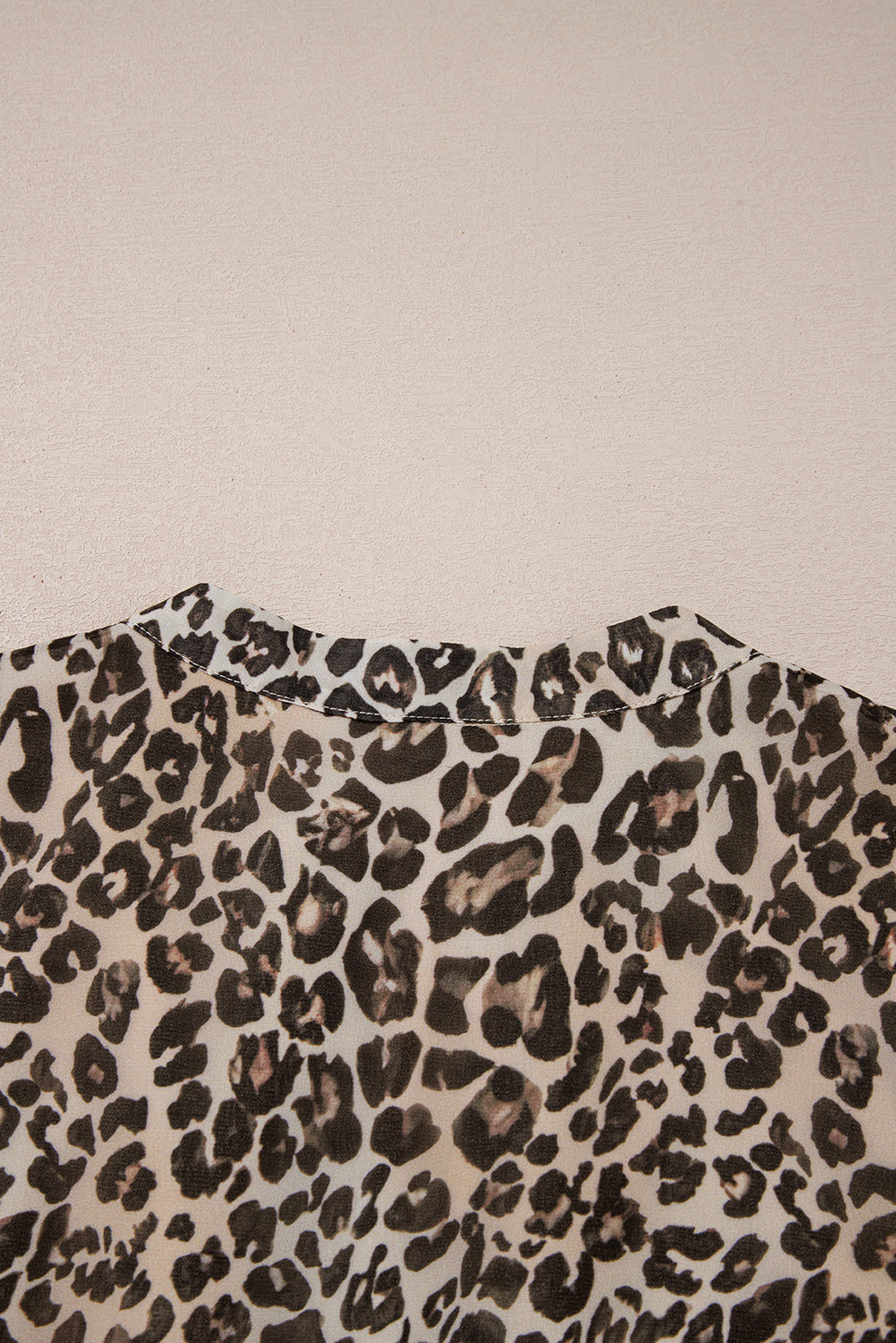 Close-up of leopard print fabric on a shirt collar against a light textured background