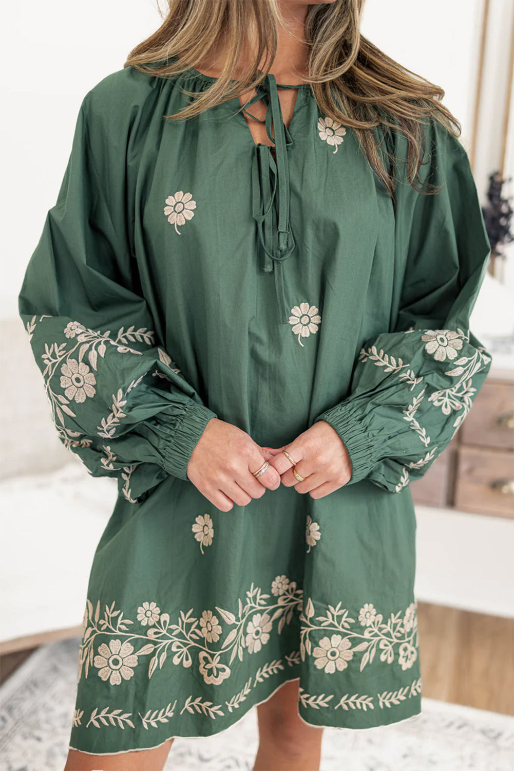 Green long-sleeve mini dress with beige floral embroidery and tie neckline, casual style