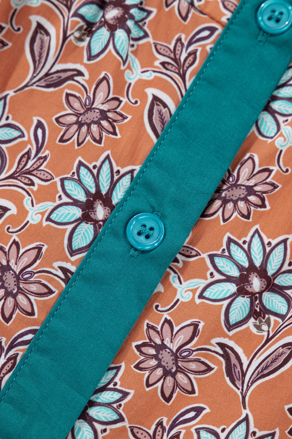Close-up of floral print fabric with teal button and teal placket