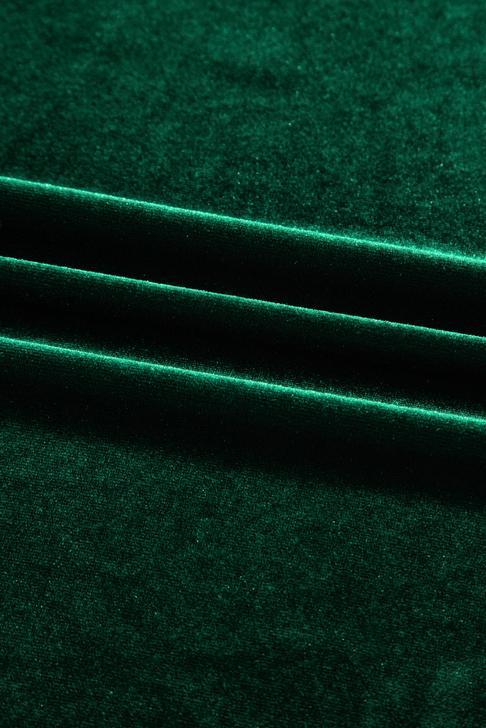 Close-up of emerald green velvet fabric with soft folds and rich texture