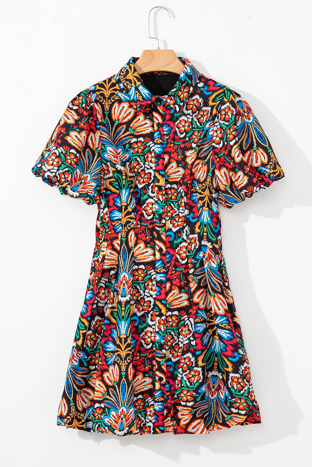 Short sleeve dress with colorful floral print and button front, hanging on wooden hanger