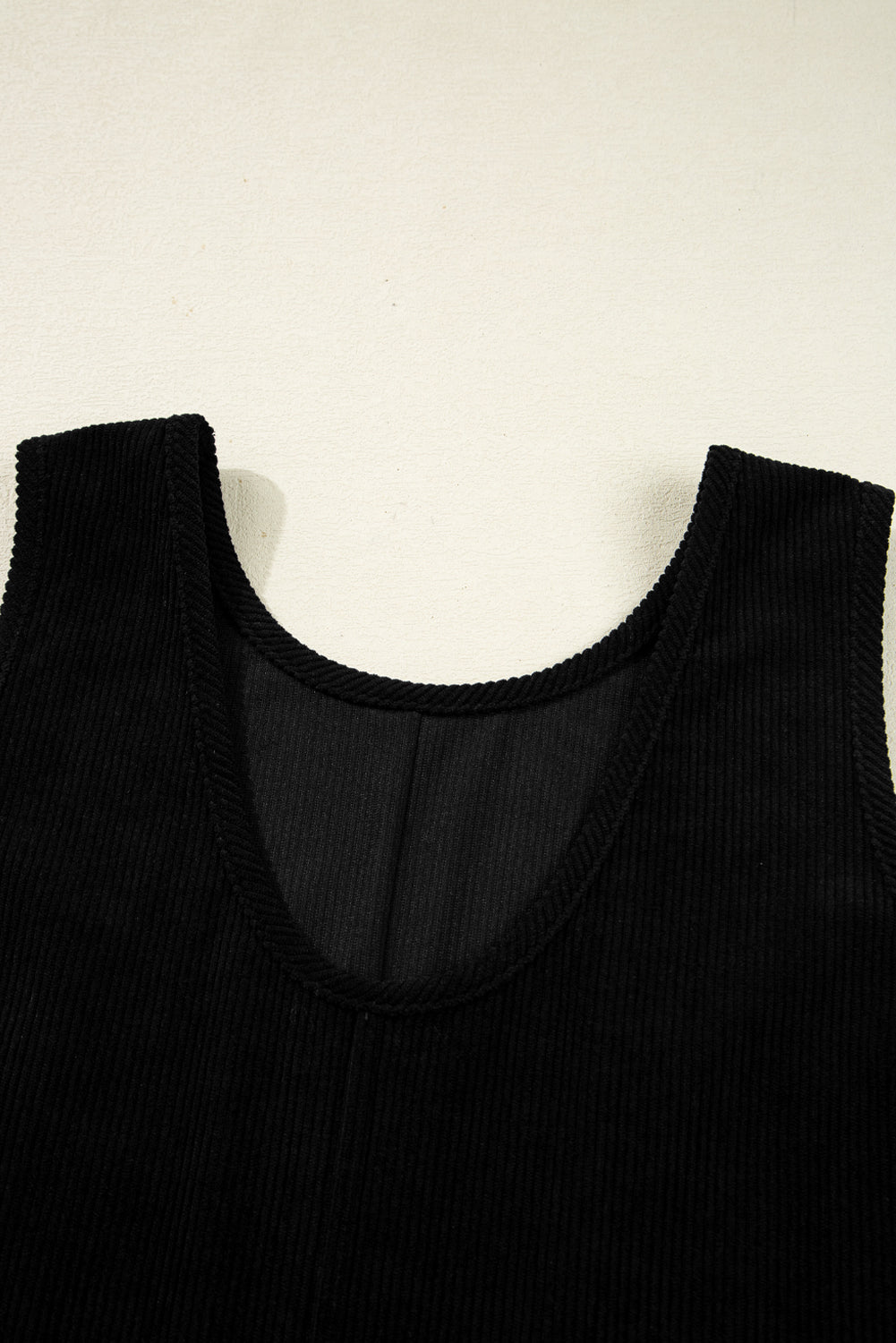 Close-up of black ribbed sleeveless top with scoop neckline on light background