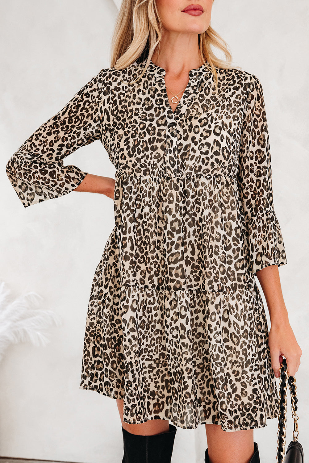 Woman in a leopard print long sleeve mini dress with ruffle hem, neutral background