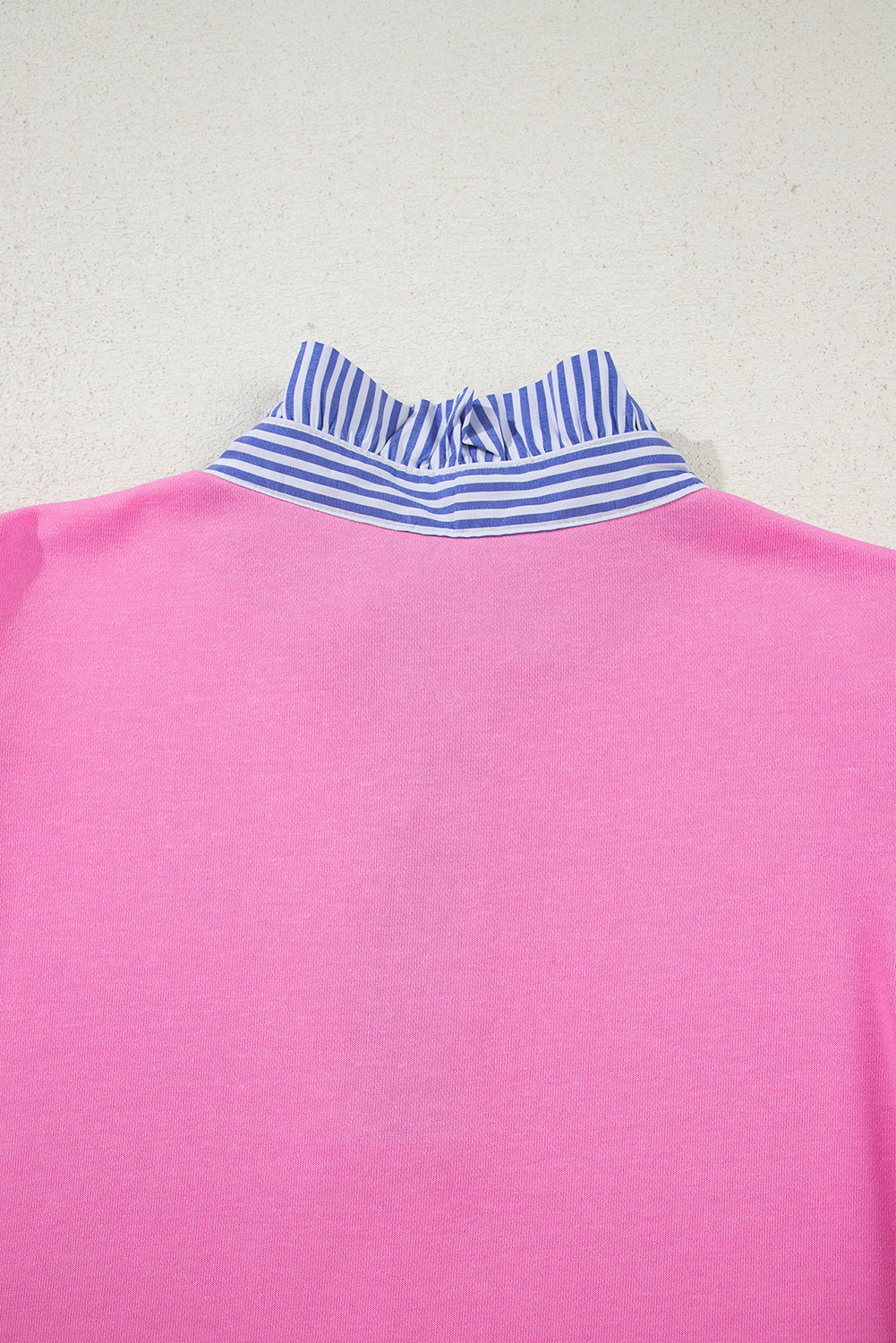 Pink top with a blue and white striped ruffled collar on a light background