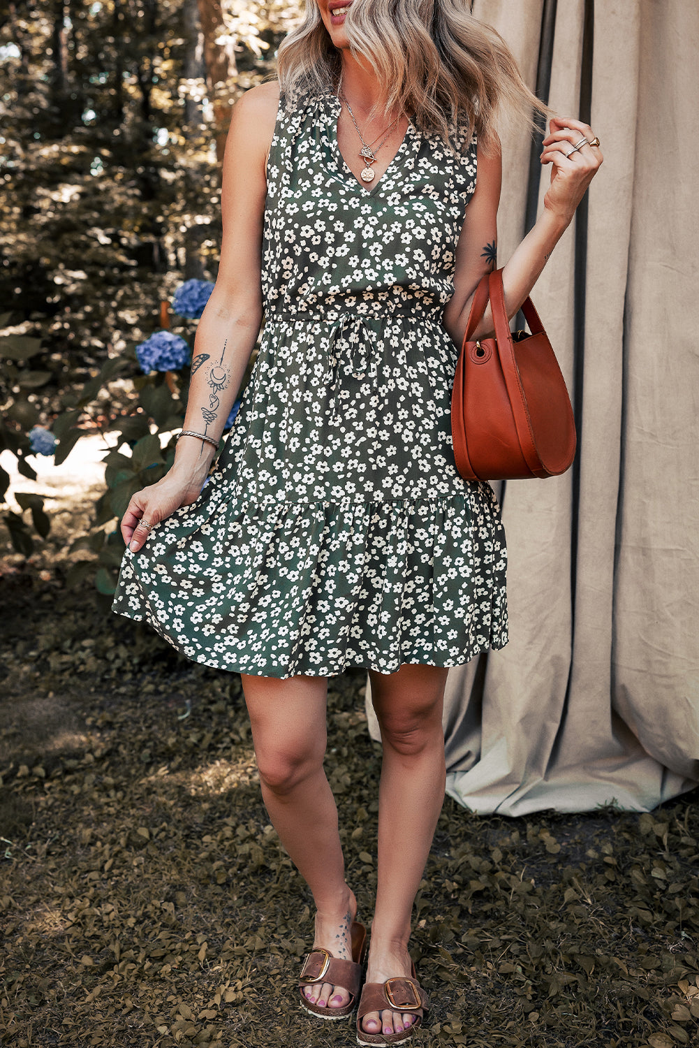 Woman wearing a green floral summer dress, brown sandals, and carrying a brown shoulder bag outdoors