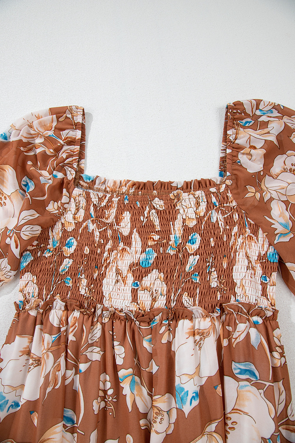 Brown floral smocked dress with puff sleeves and blue accents, laid flat on white background.