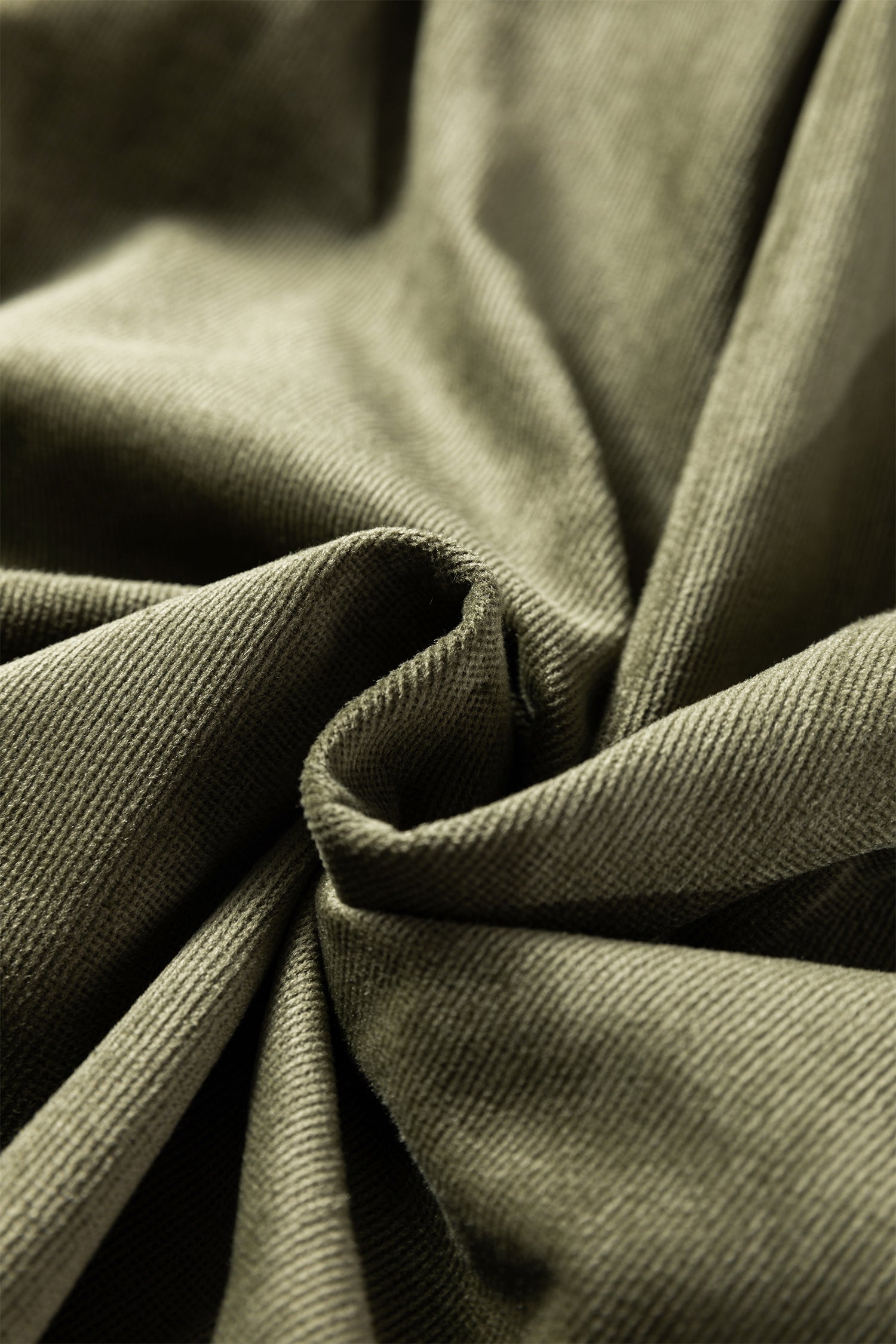 Close-up of olive green corduroy fabric texture with soft folds