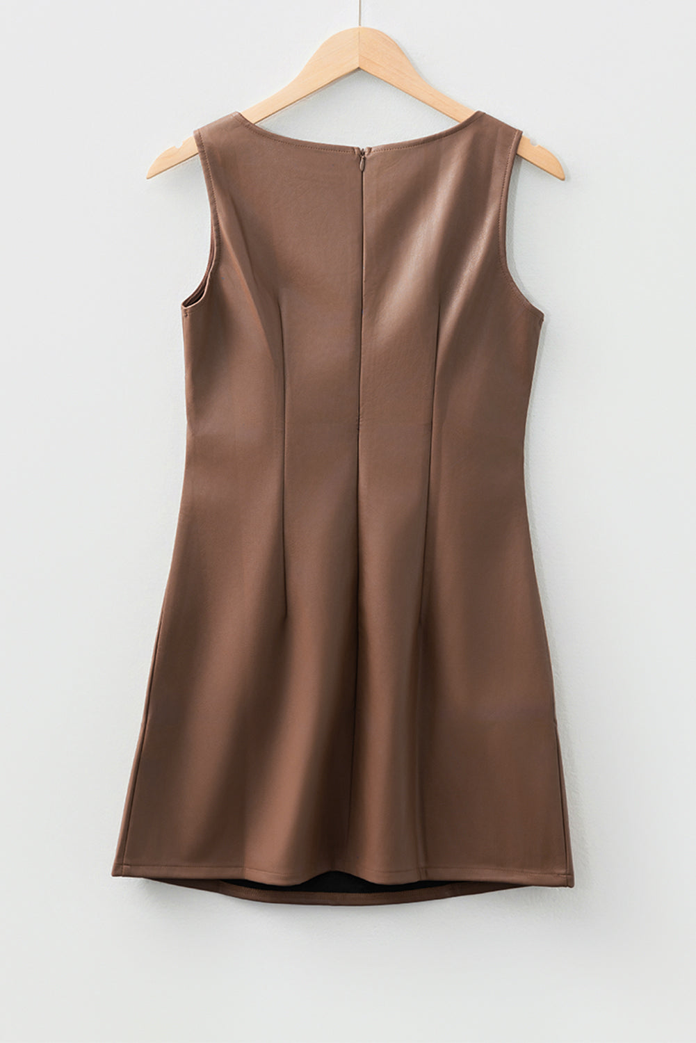 Sleeveless brown faux leather dress on wooden hanger, minimalist background