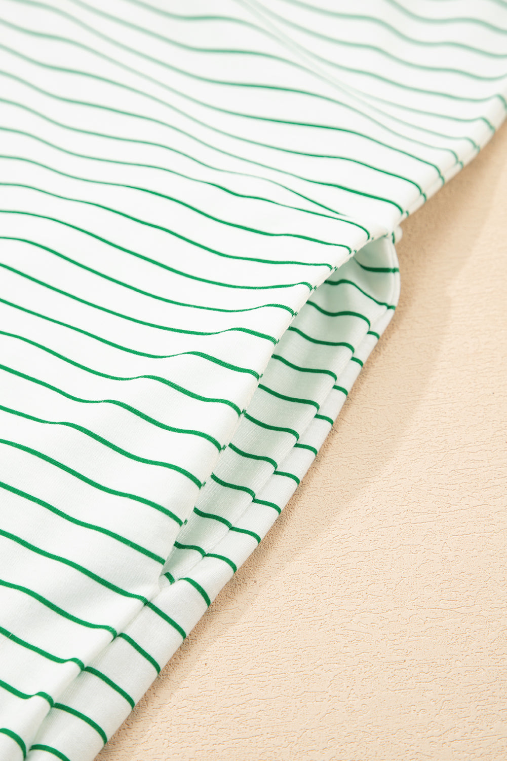 Close-up of white fabric with green horizontal stripes, soft cotton texture