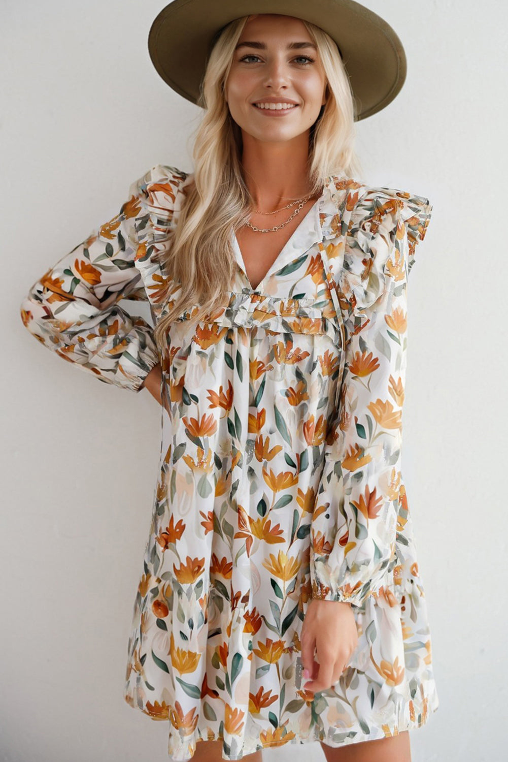 Woman in a floral long-sleeve dress with ruffles and wide-brim hat, smiling indoors