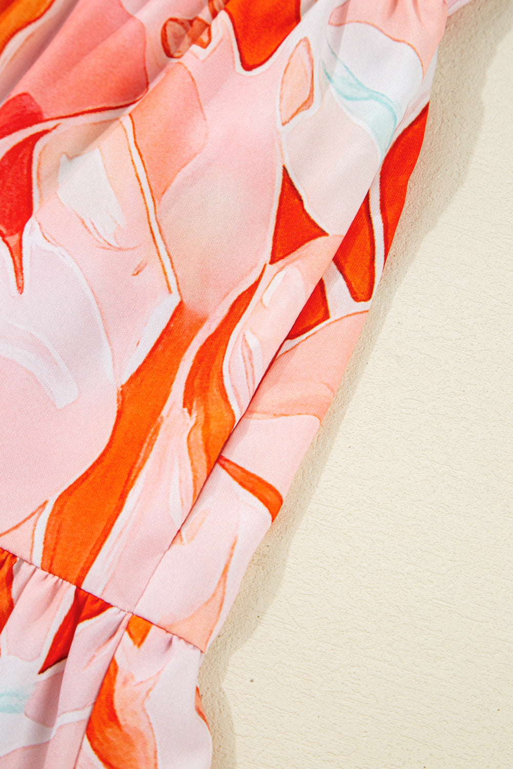 Close-up of fabric with pink and orange abstract floral print and gathered detail