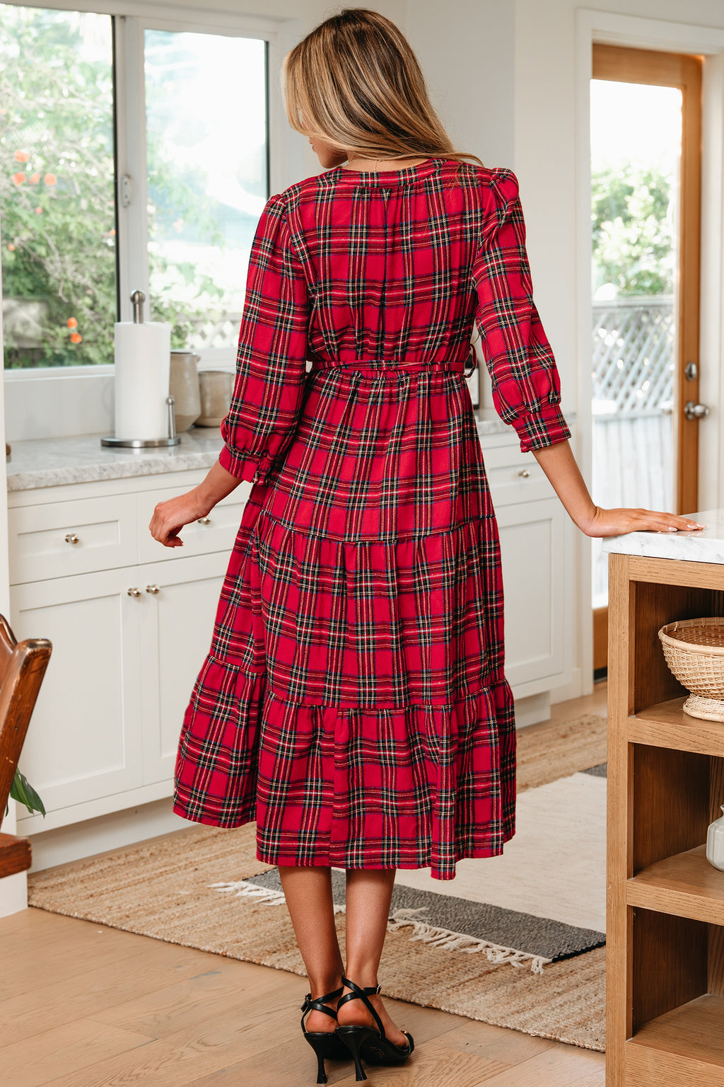 Woman wearing red plaid midi dress with long sleeves in modern kitchen