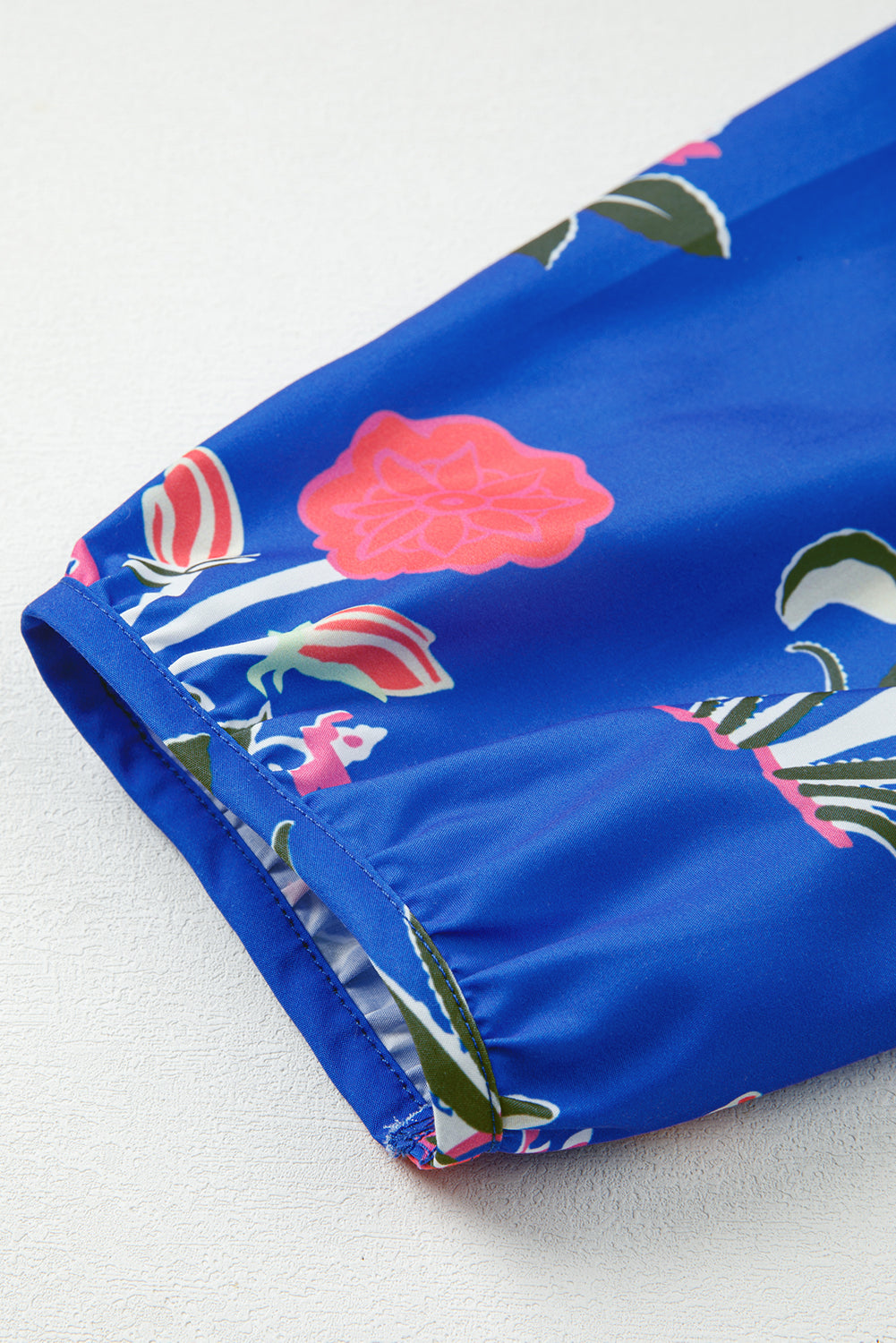 Blue floral print fabric sleeve with elastic cuff detail on smooth white surface