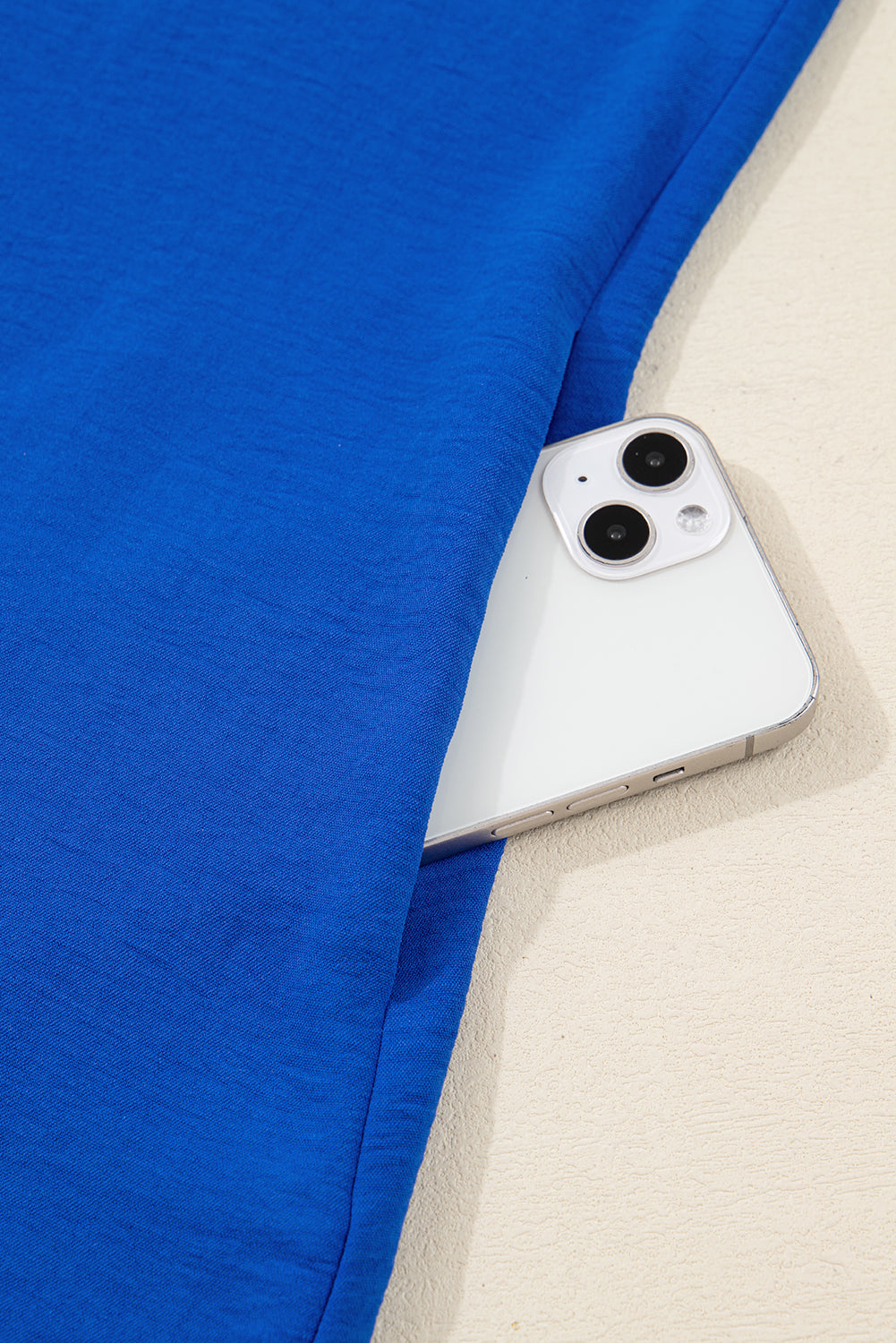 White smartphone in blue fabric pocket on light background