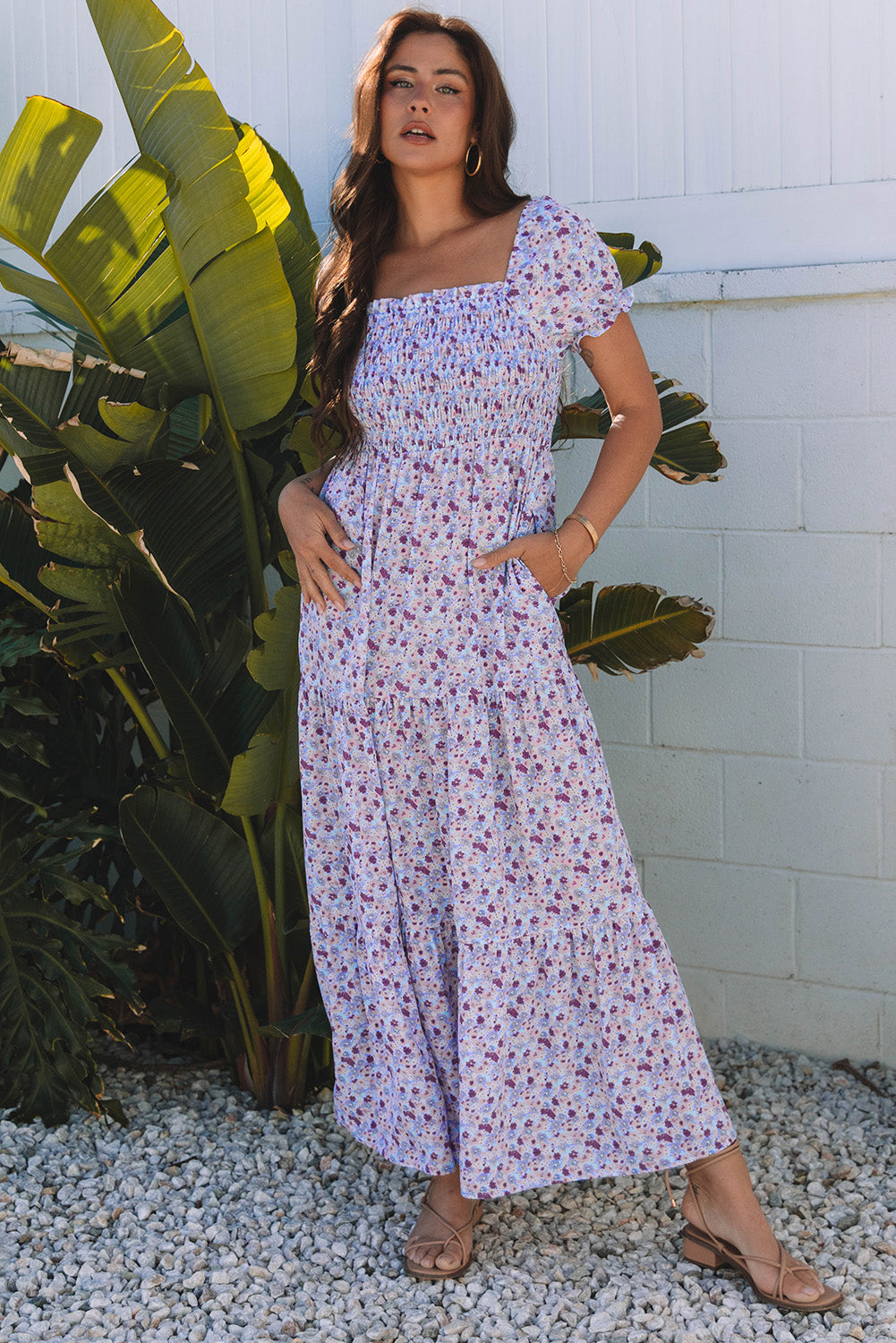 Woman in floral maxi dress with puff sleeves, standing outdoors by green tropical plants