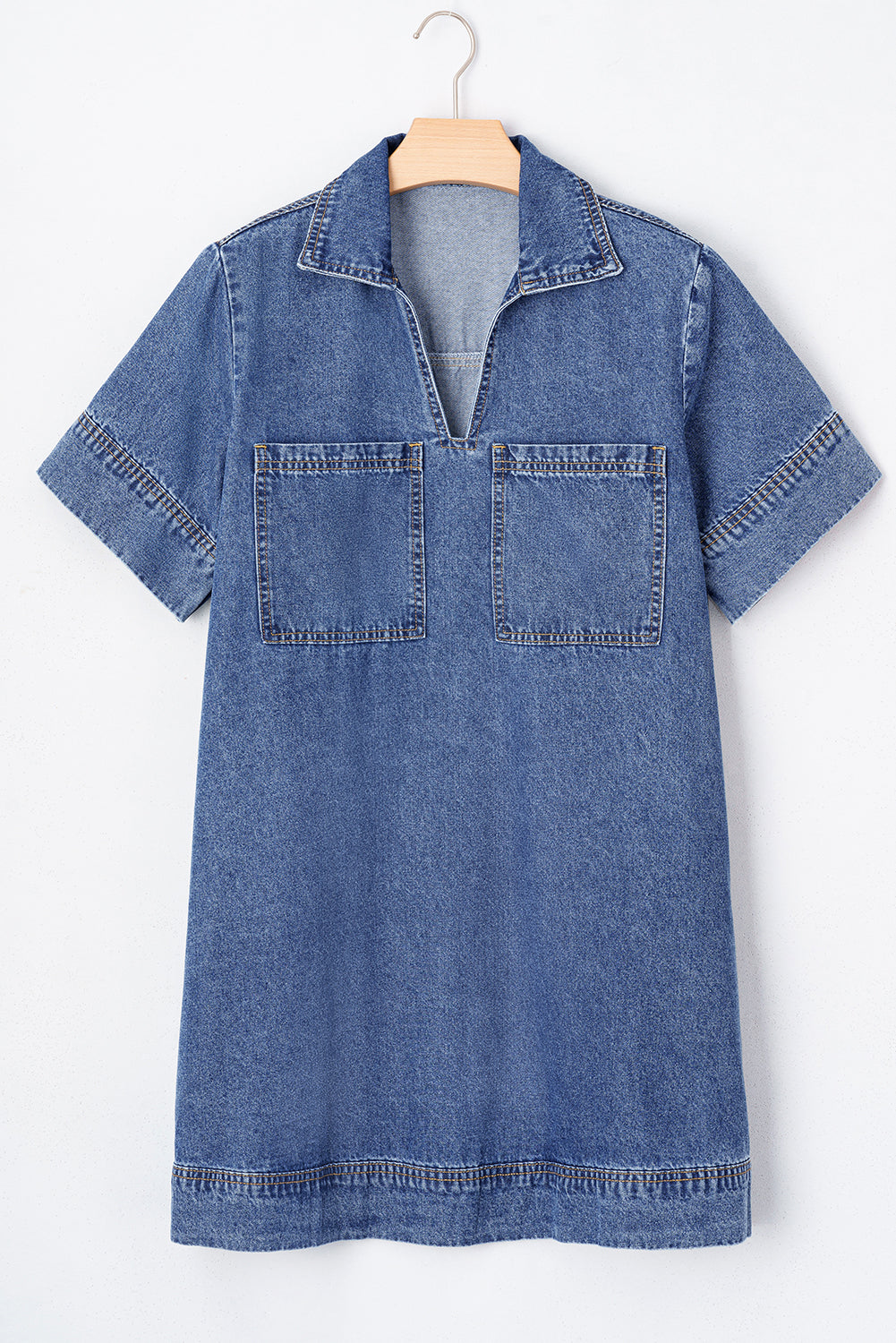 Short sleeve denim dress with front pockets and a split collar, hanging on a wooden hanger.