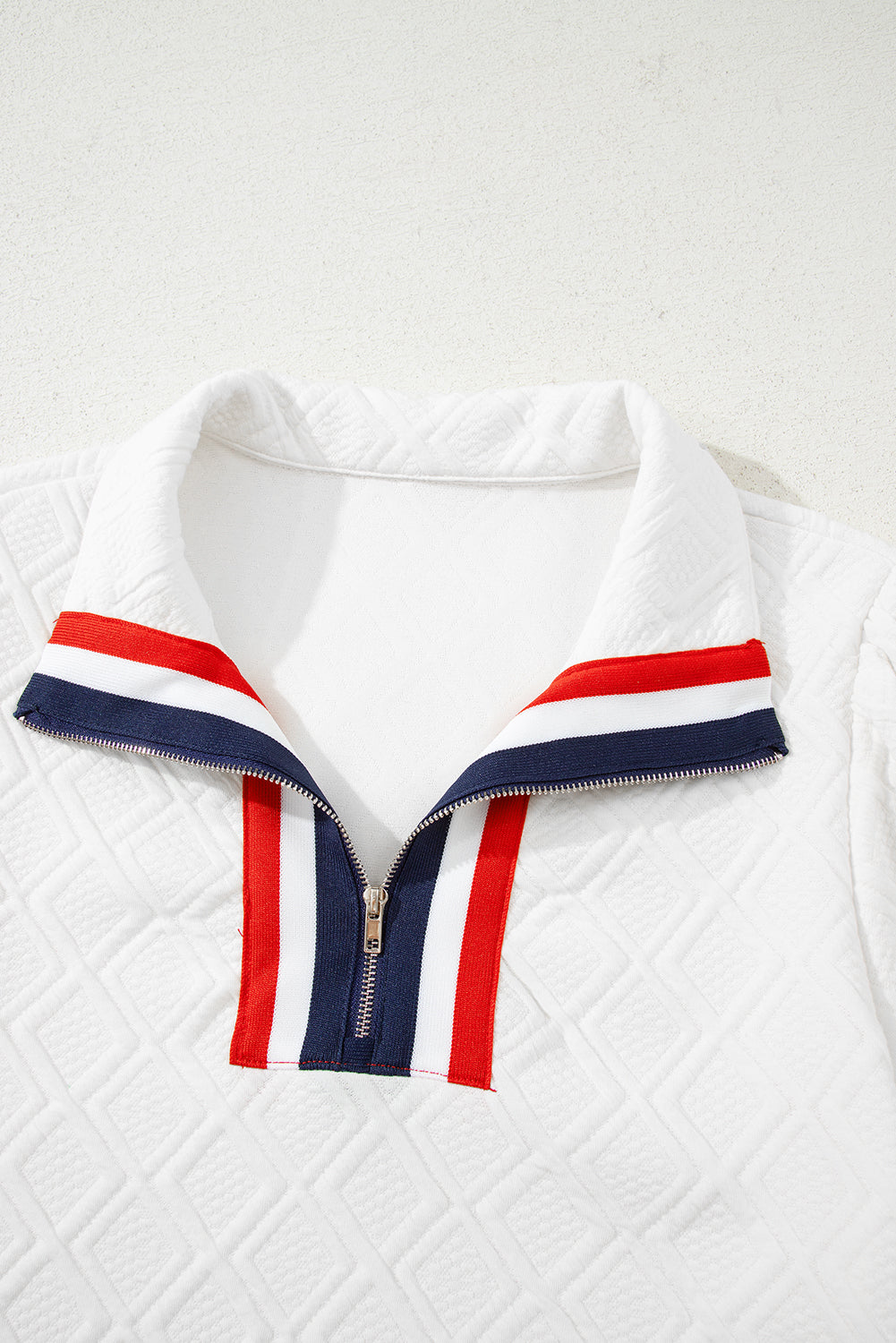 White quilted pullover with red, white, and navy striped zip collar detail