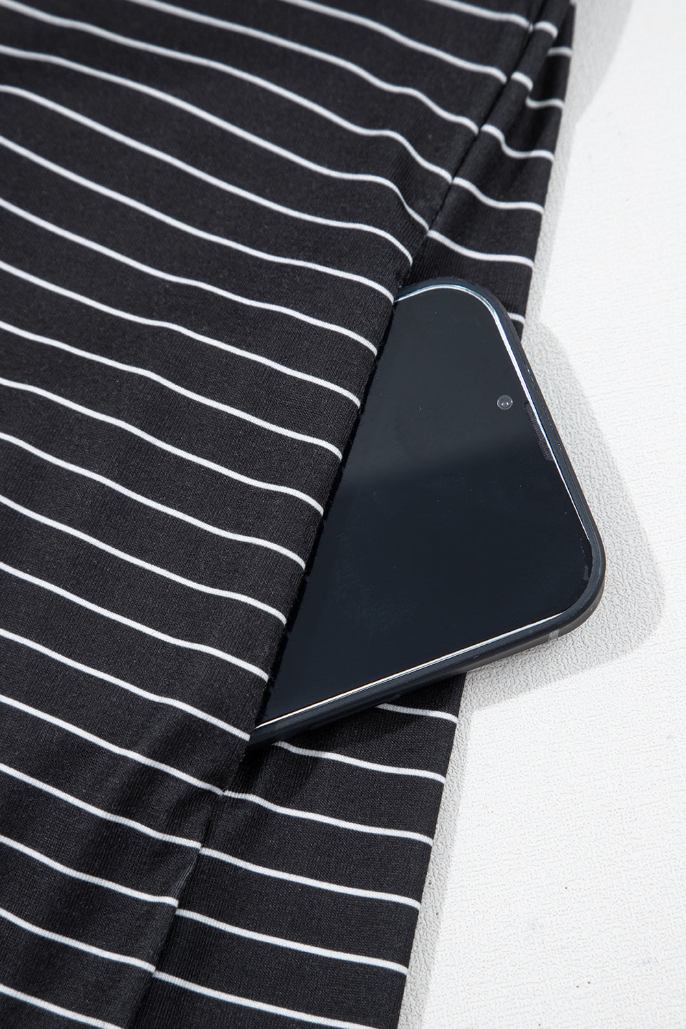 Black and white striped fabric pocket with smartphone inside, close-up