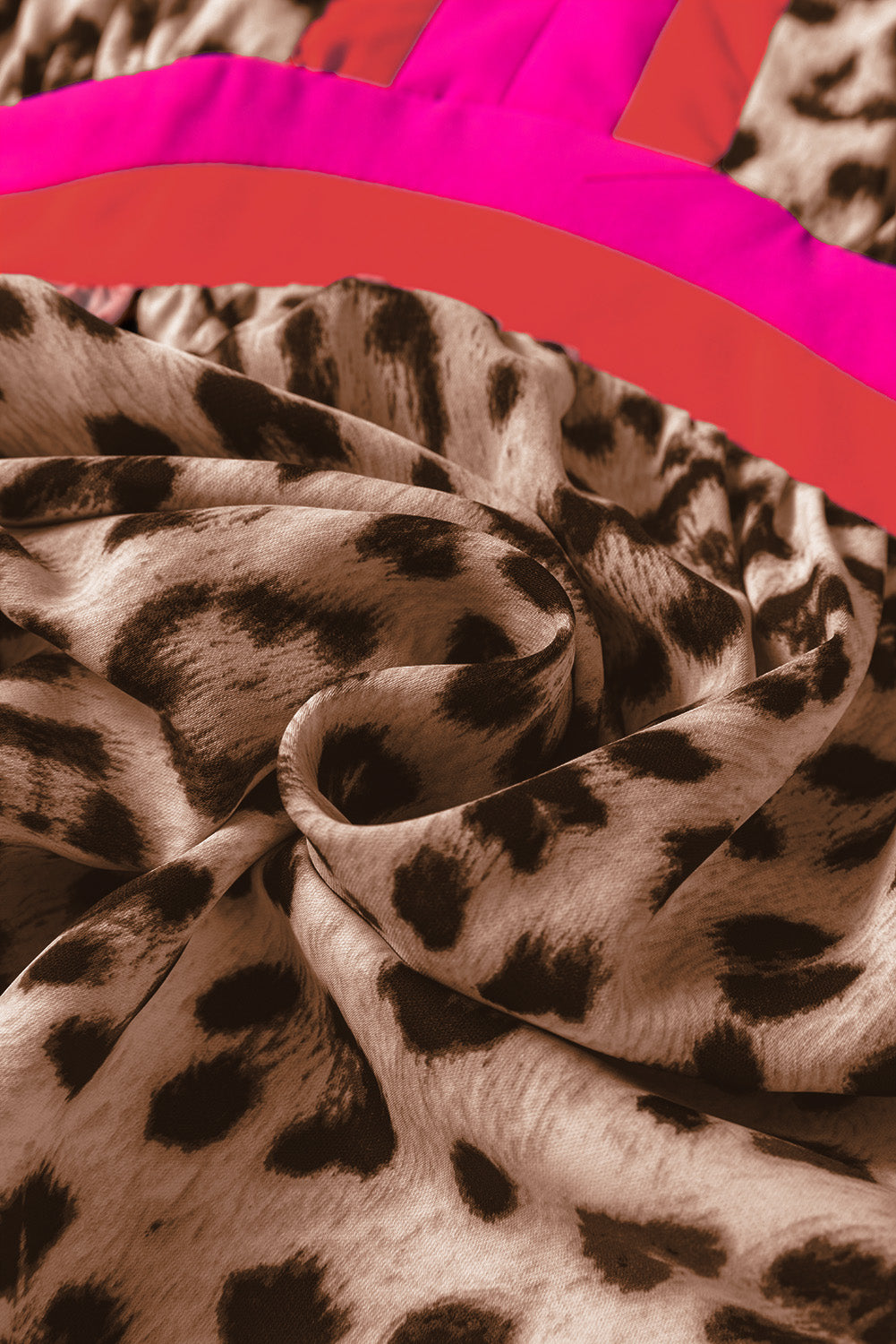 Leopard print fabric with vibrant pink and red stripe detail, close-up texture