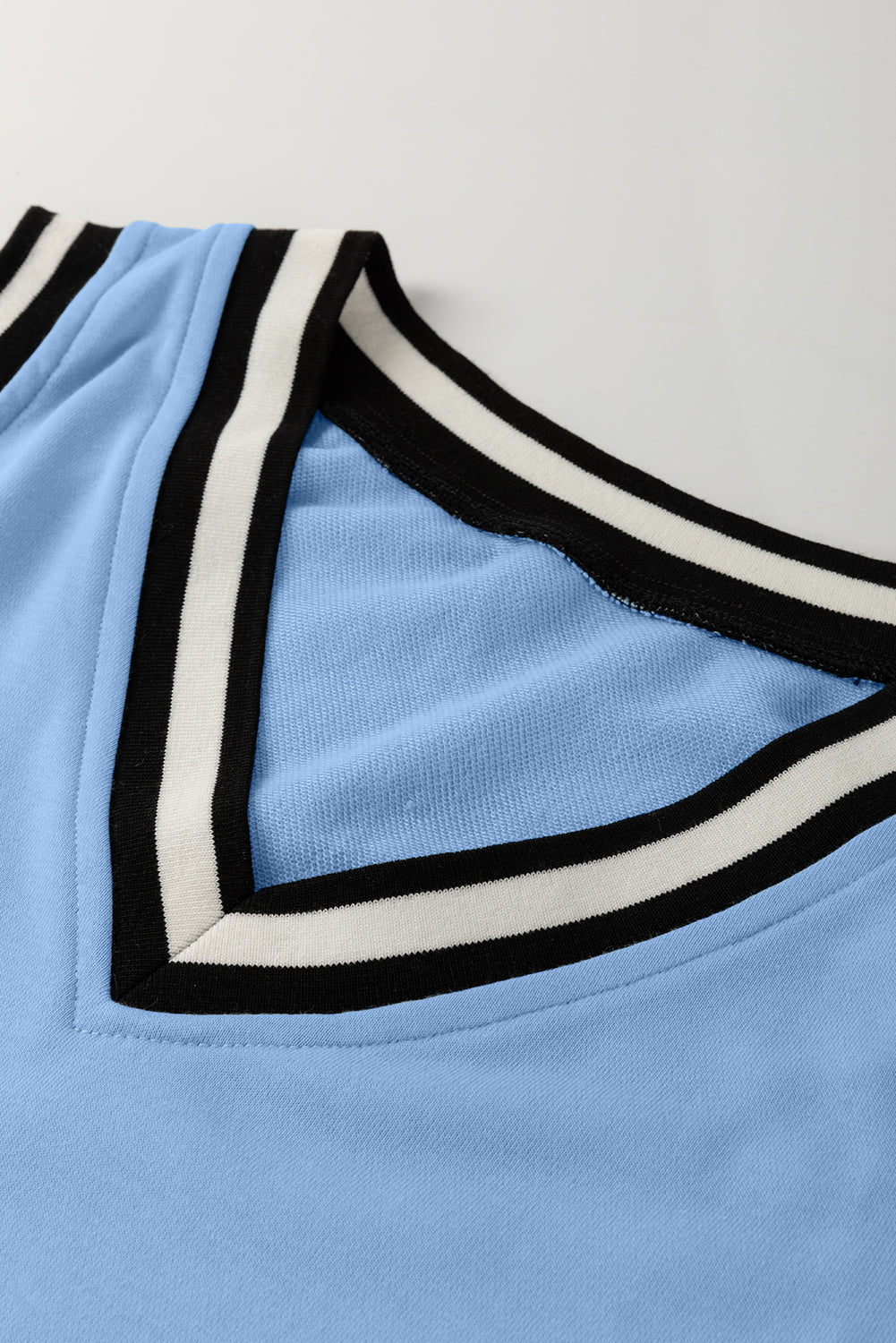 Light blue V-neck top with black and white striped trim, close up on collar
