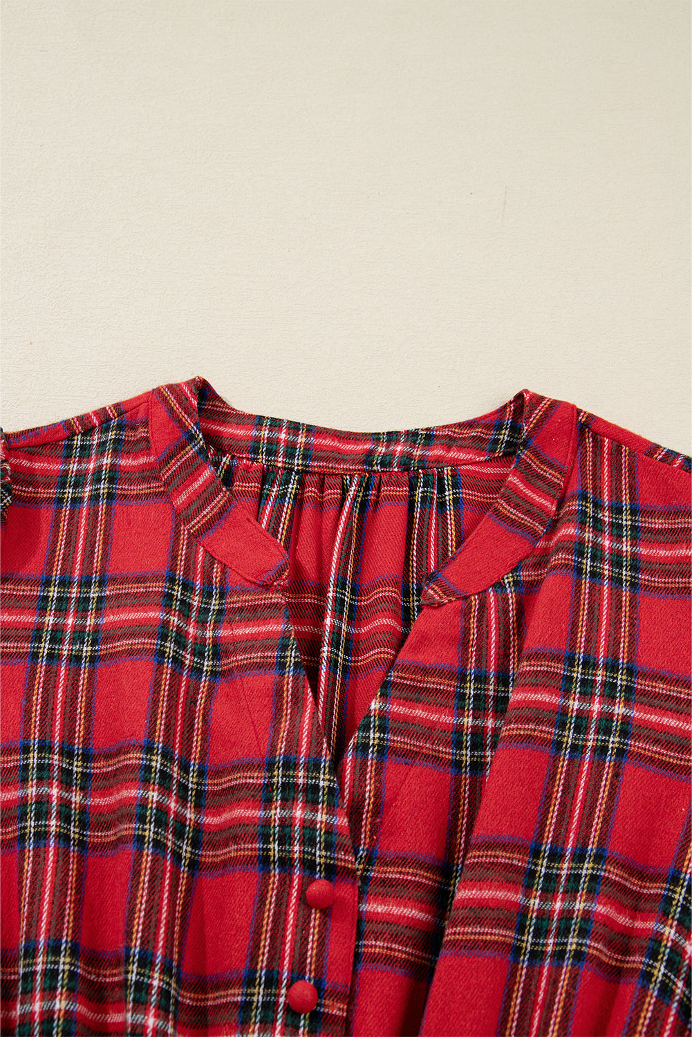 Close-up of red plaid button-up shirt with V-neck and gathered detailing