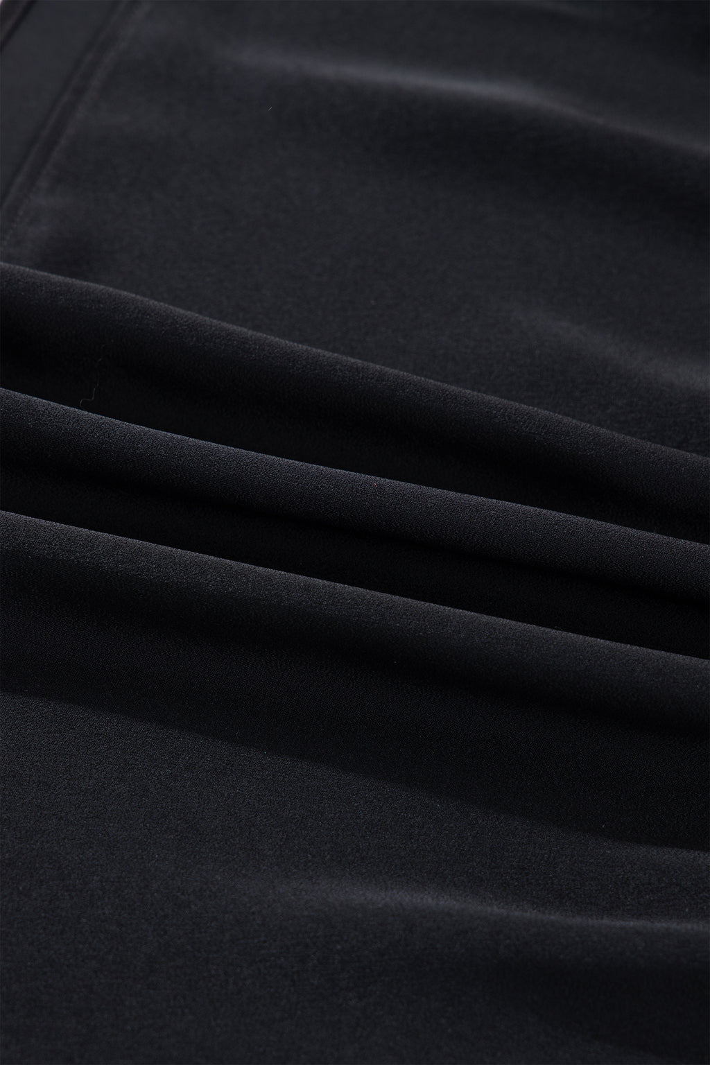 Close-up of soft black velvet fabric with smooth folds and a matte finish texture