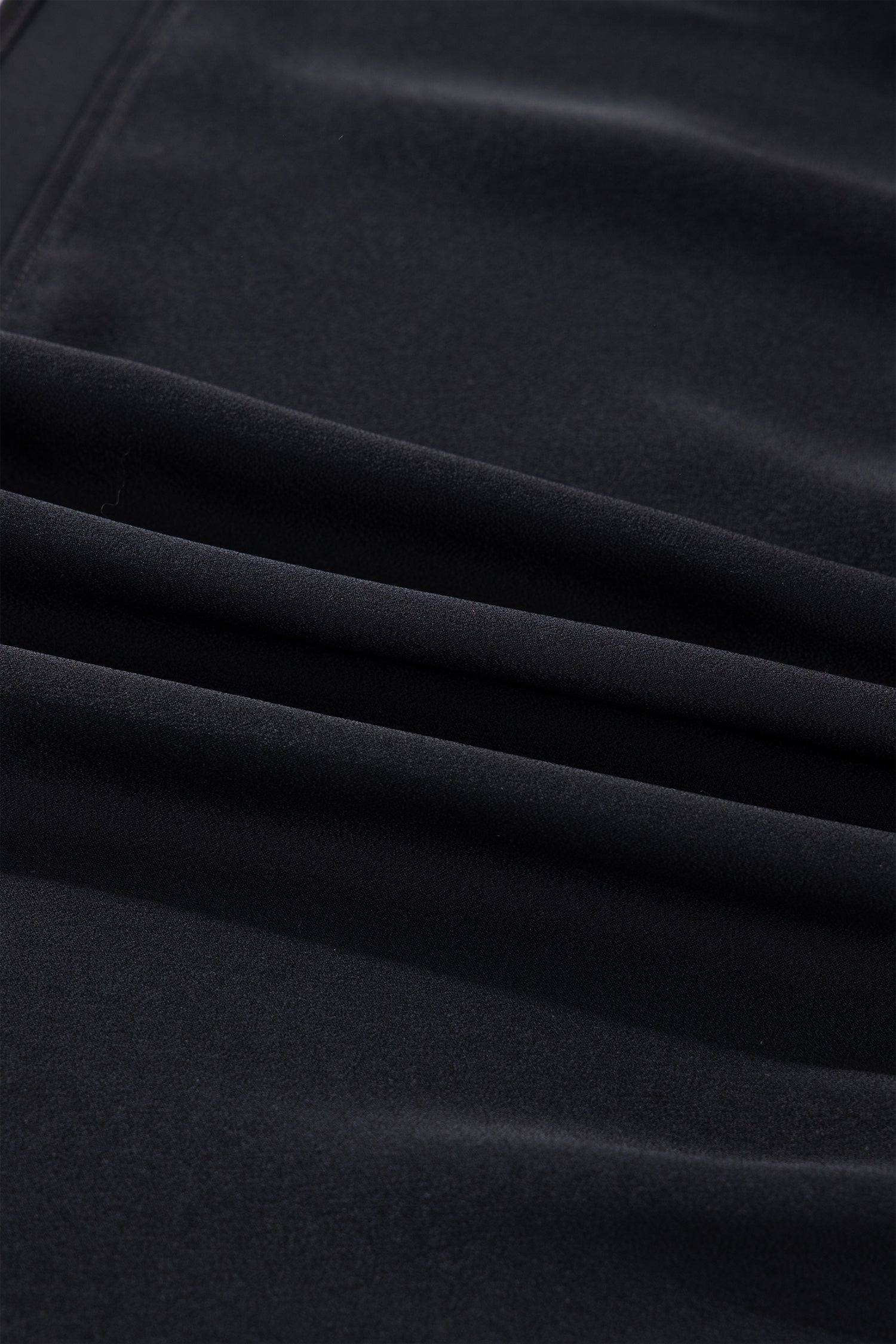 Close-up of soft black velvet fabric with smooth folds and a matte finish texture