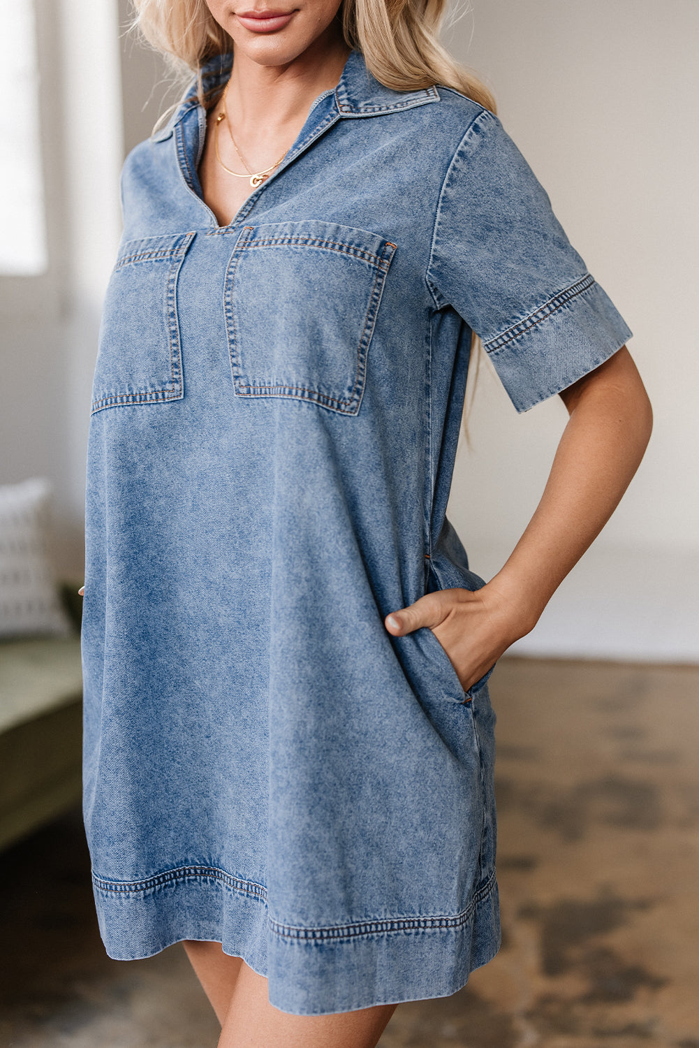 Woman wearing a short sleeve denim dress with front pockets in a casual indoor setting