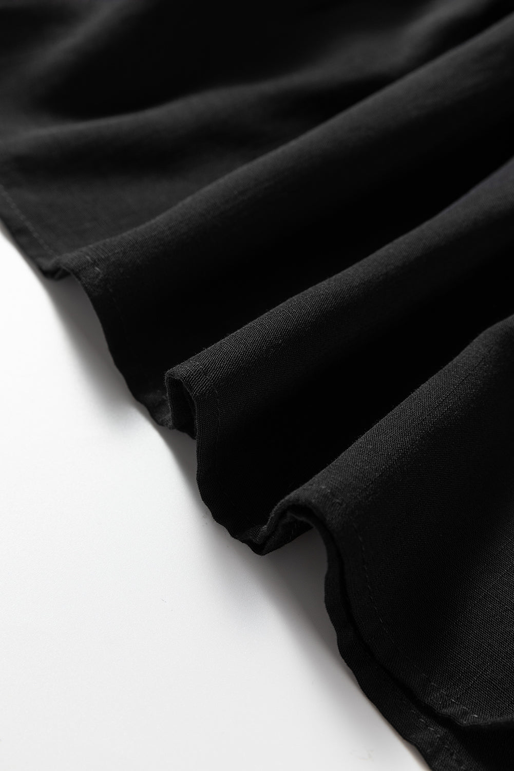 Close-up of black fabric with soft textured folds on a white surface