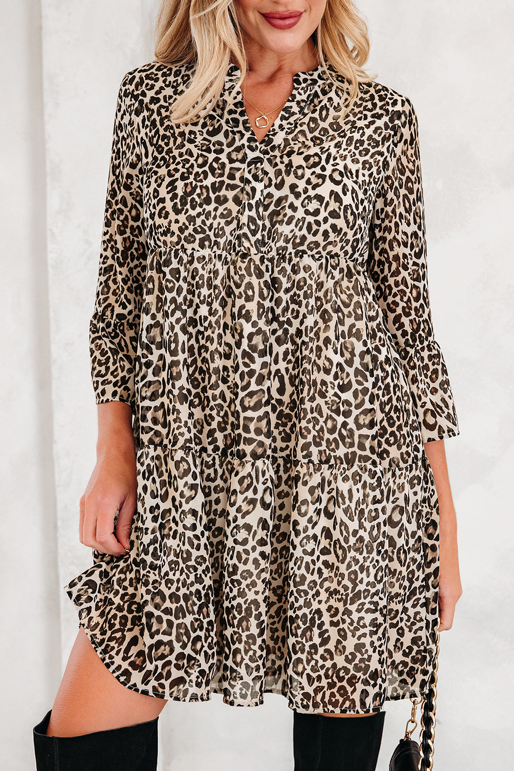 Woman wearing a long sleeve leopard print dress with black knee-high boots