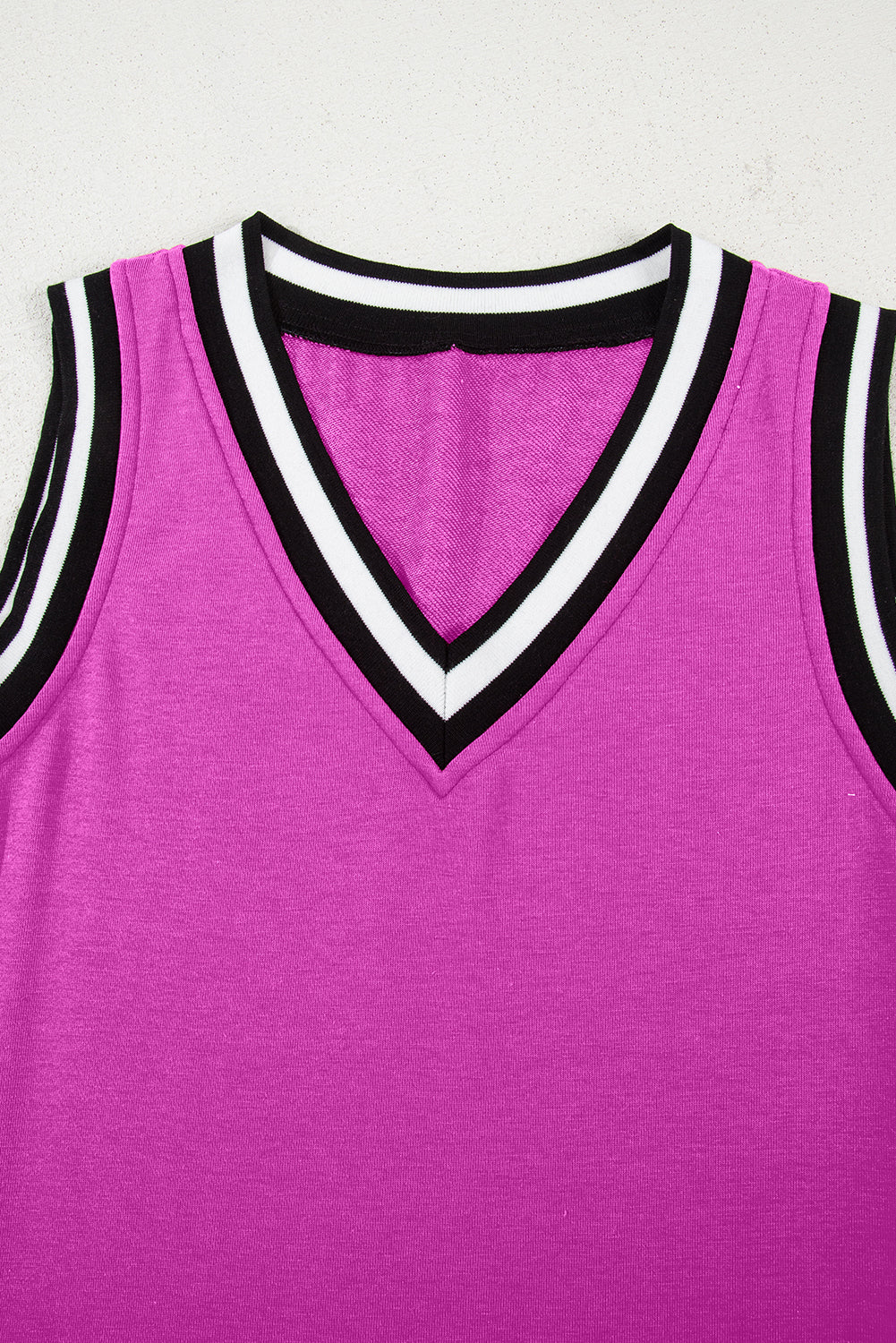 Sleeveless magenta V-neck top with black and white striped trim on collar and armholes