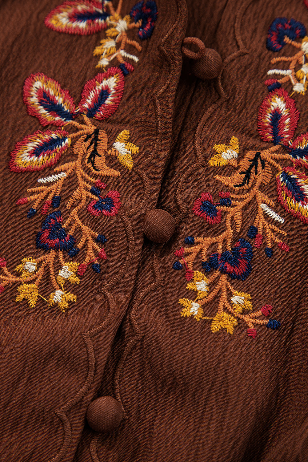 Brown textured fabric with colorful floral embroidery and fabric-covered buttons