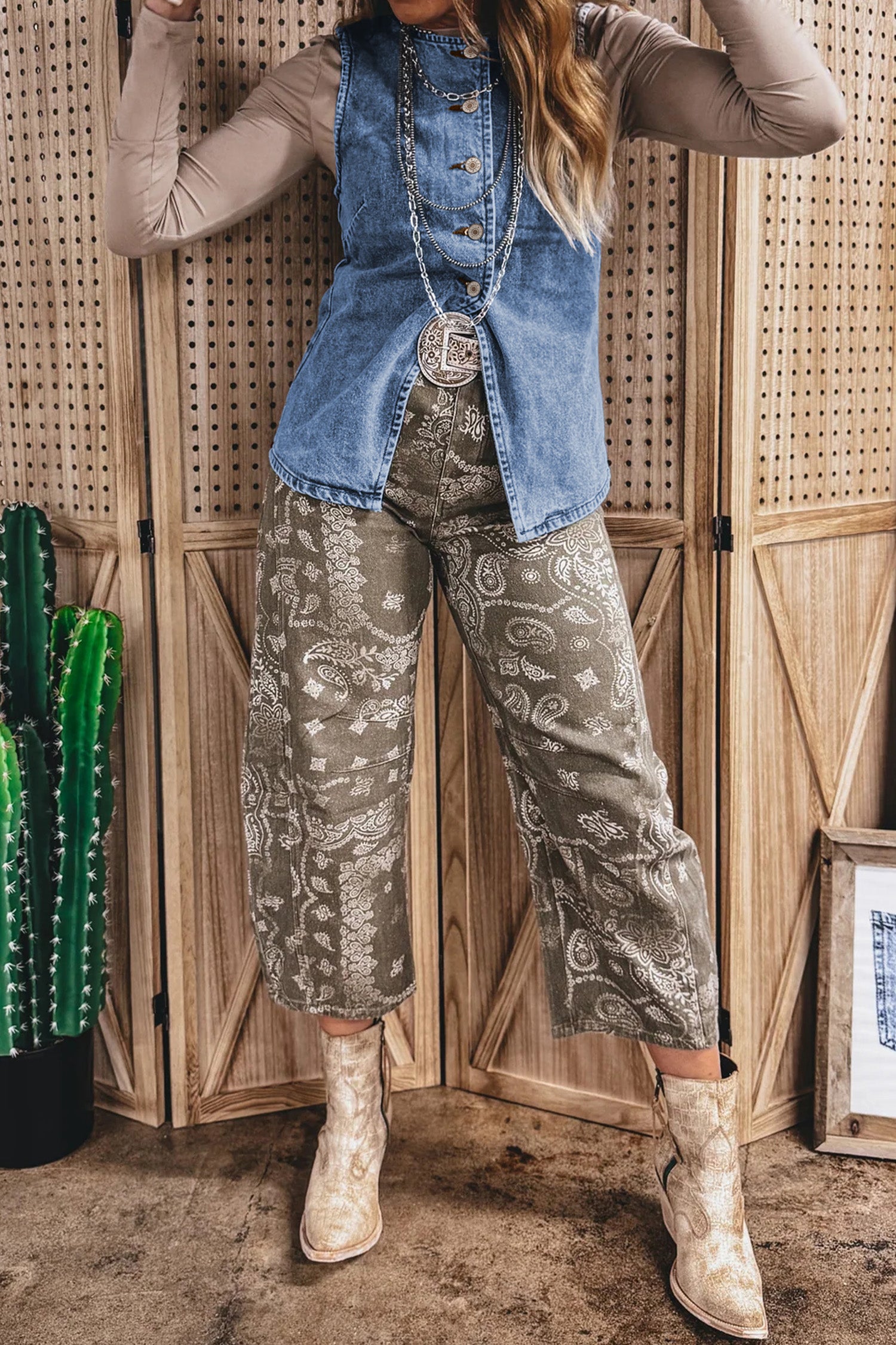 дамски син дънков елек, носен с бежова блуза с дълъг ръкав, принтован панталон и бежови каубойски боти