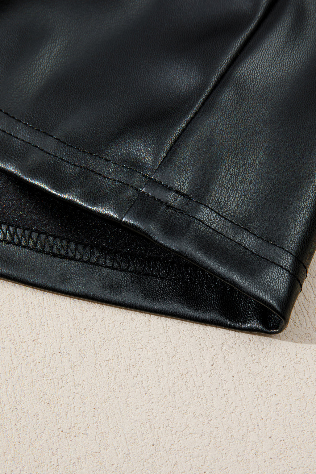 Close-up of black faux leather fabric with visible stitching detail