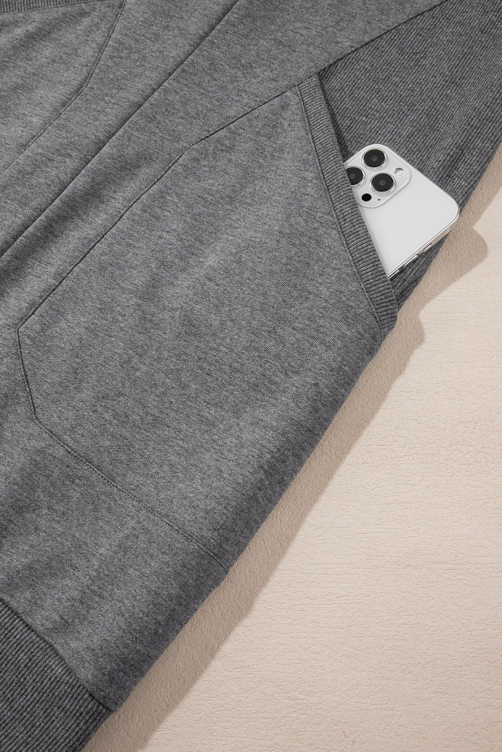 Gray sweatpants with ribbed cuff and smartphone in pocket, close-up view