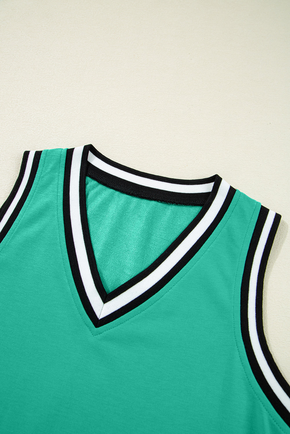 Green sleeveless V-neck top with black and white striped trim detail