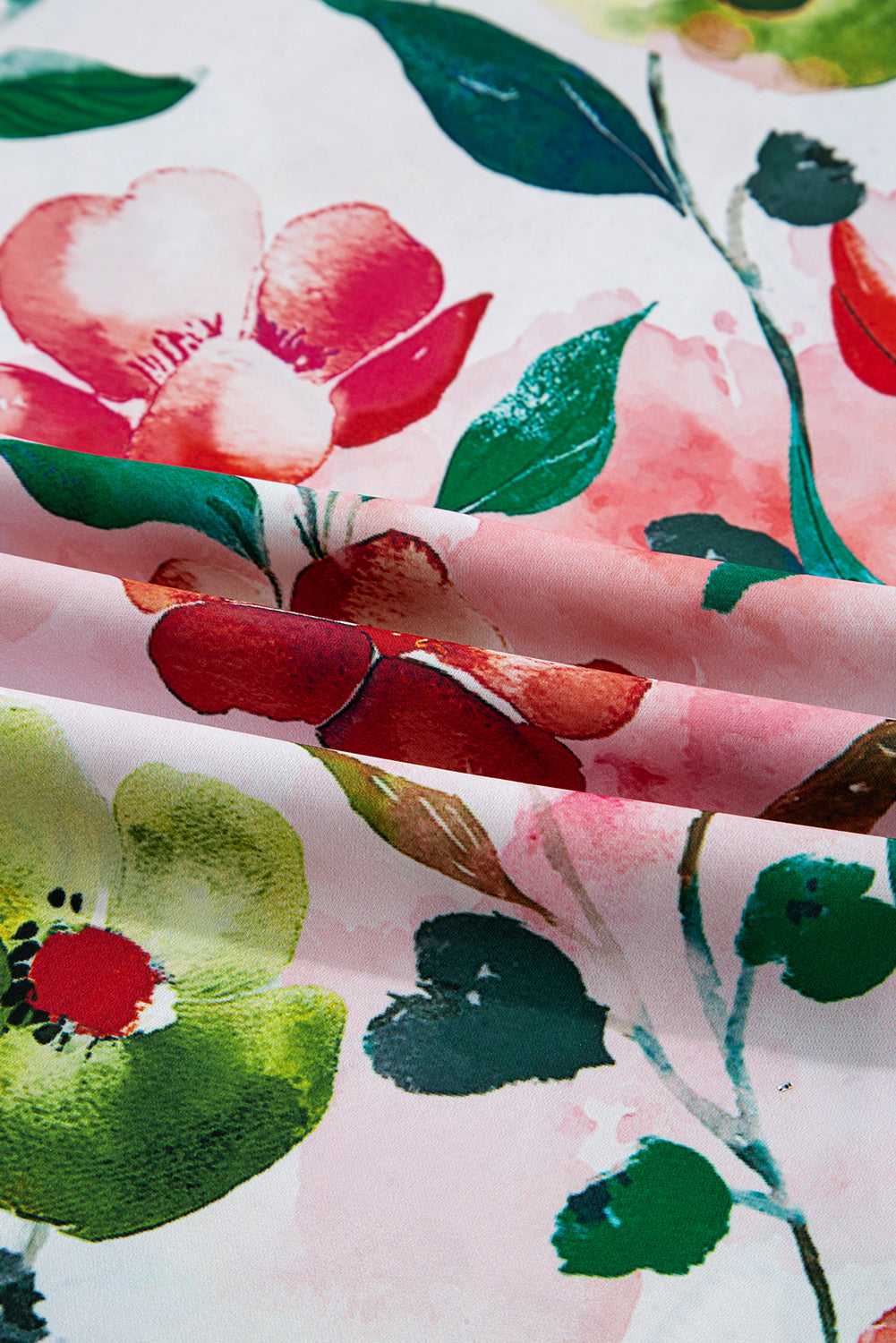Close-up of soft fabric with pink, red, and green watercolor floral print pattern.