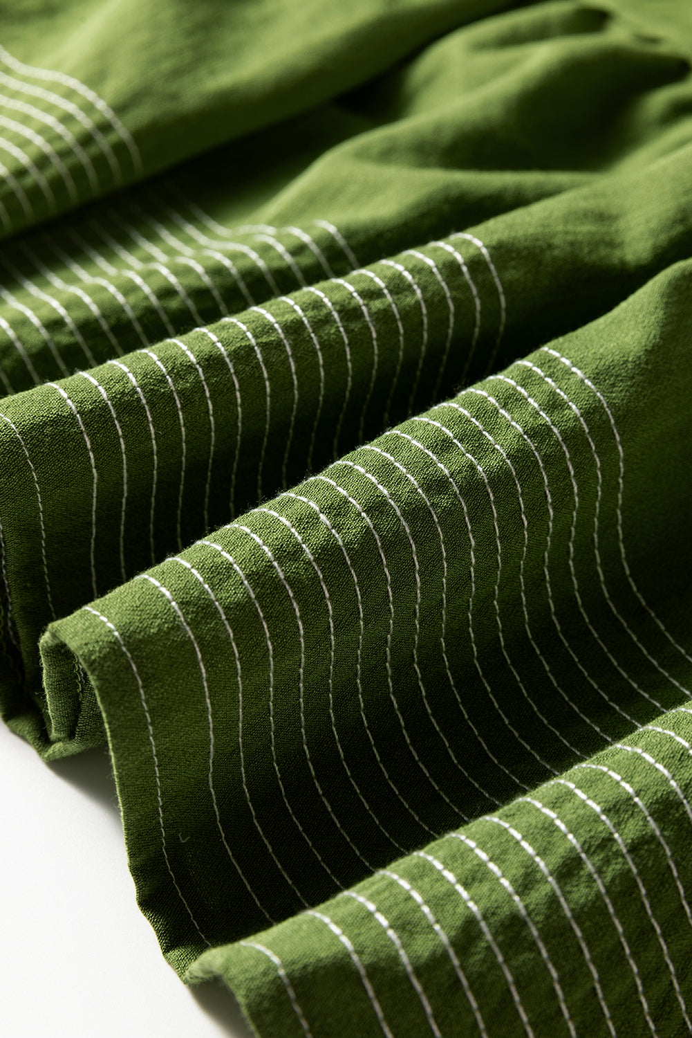 Close-up of green fabric with white horizontal stripes, textured and folded